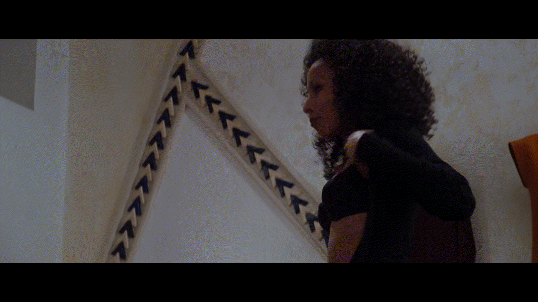 Tamara Tunie undressing in The Devil's Advocate, transitioning from a black bra to topless with a white woman assisting.