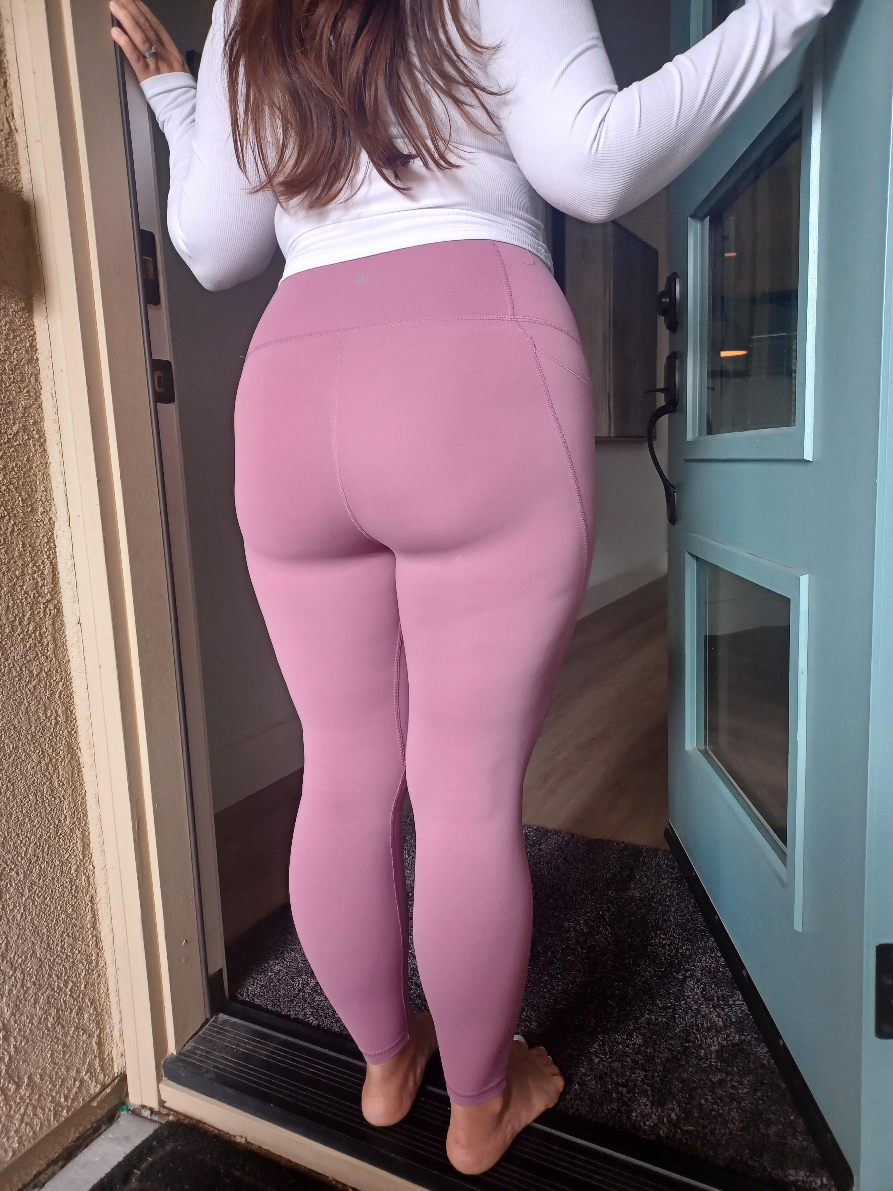 White brunette pawg in pink leggings and a white long-sleeve shirt posing to show off her big ass in a pelfie.