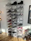 Sneaker collection in clear storage boxes on a wooden floor with a color theory chart and framed poster.