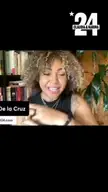 A brown-skinned woman with curly brown hair and a tattoo on her left arm speaking about late stage capitalism.