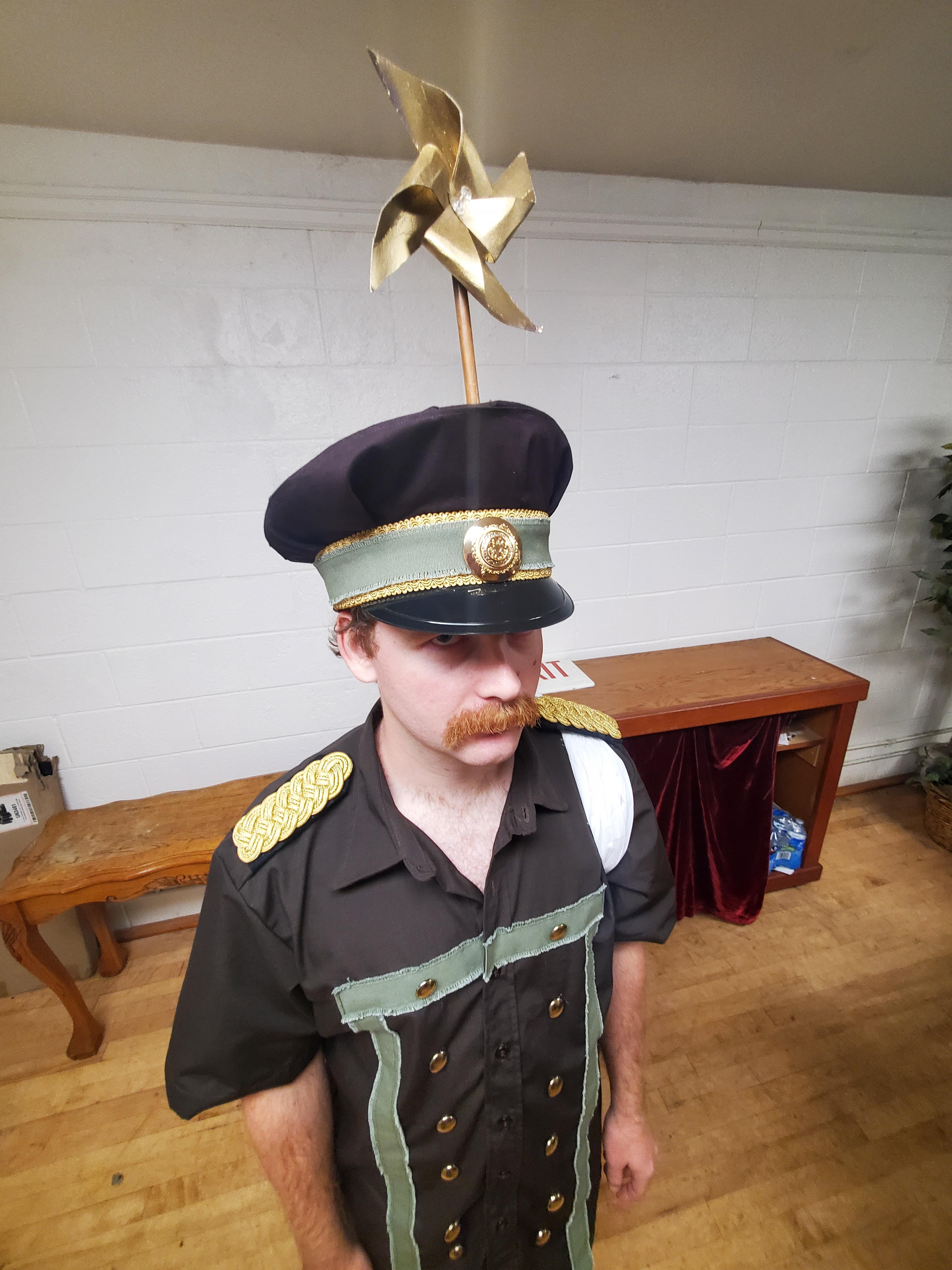 Genzo cosplay from One Piece featuring a man in a black captain's costume with short shorts and a gold pin hat