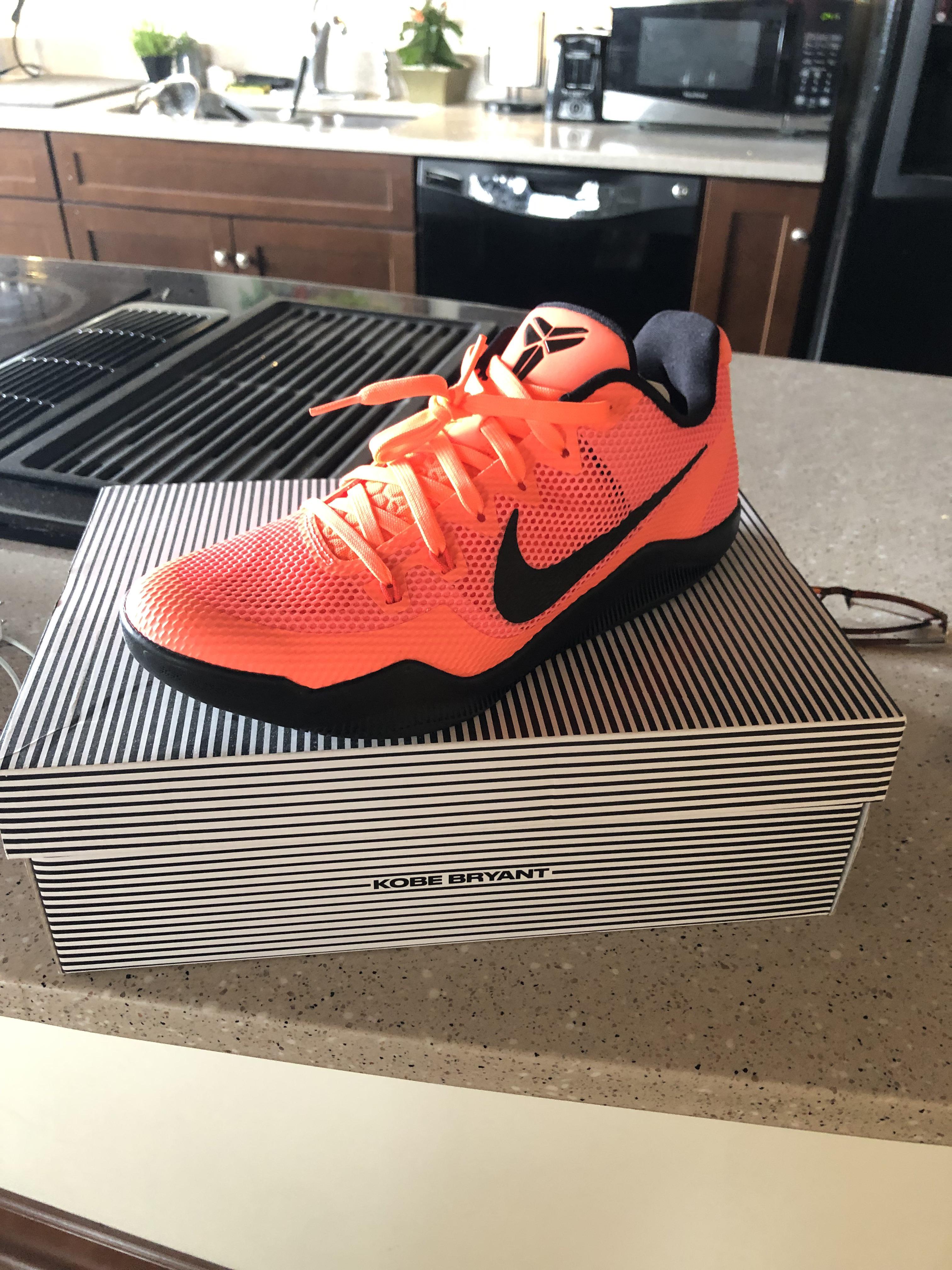 Bright orange Nike sneakers with black swooshes in a shoebox, as worn by Jordan Poole