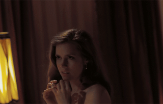 Amy Adams topless and smiling in a dimly lit room from American Hustle