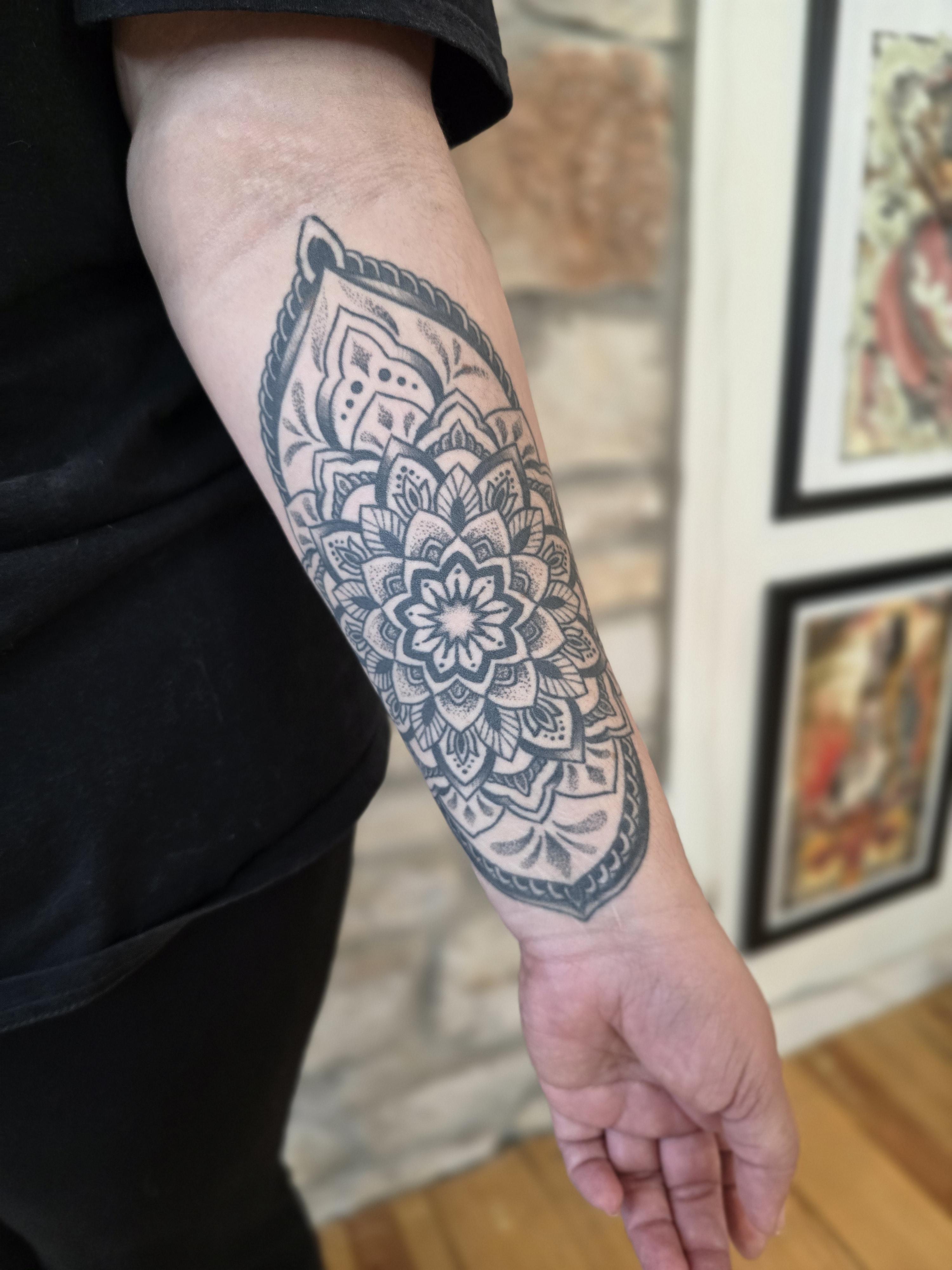 Healed black ink mandala tattoo on a person's forearm by Kevin Daniels