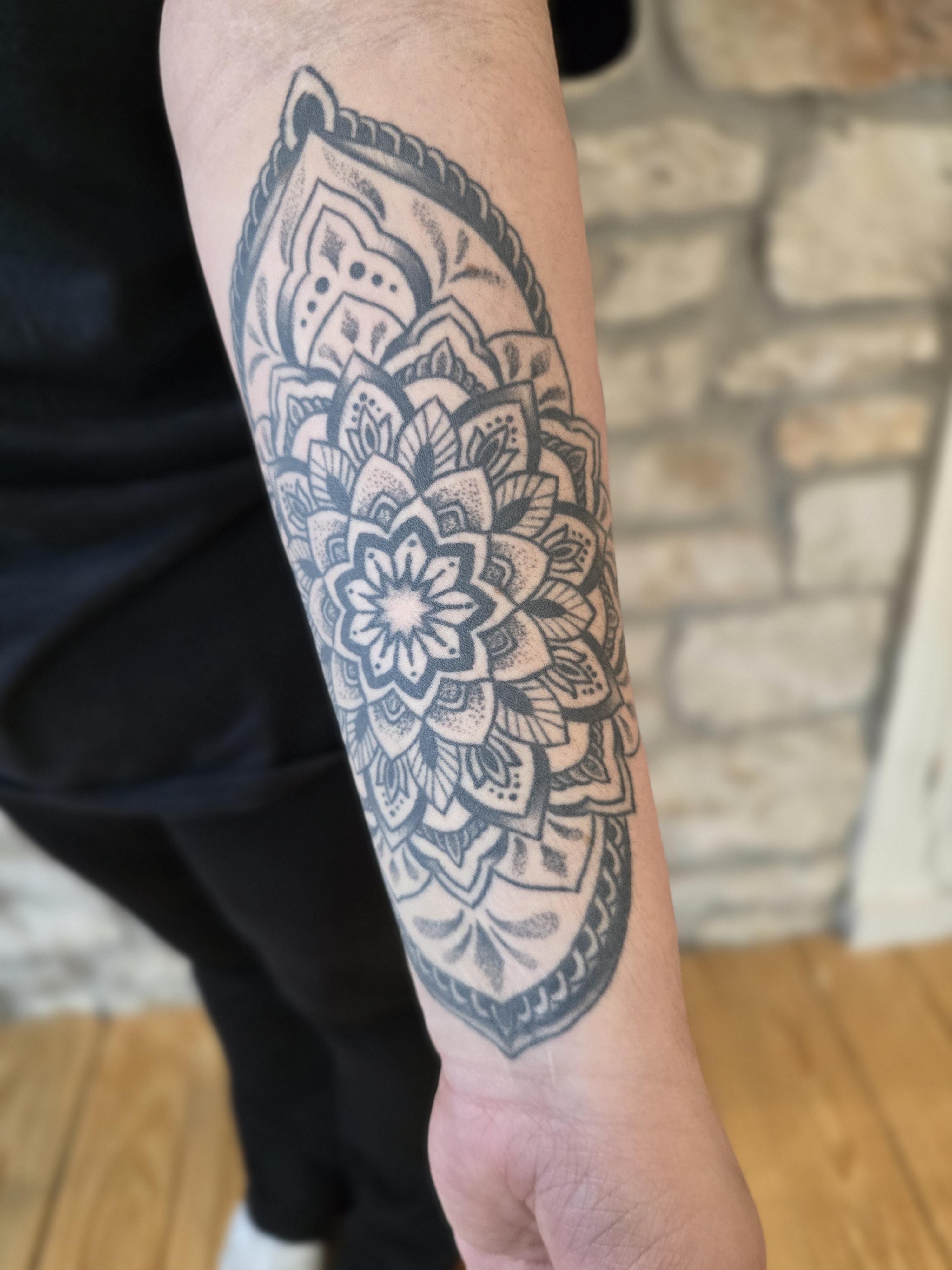 Healed black ink mandala tattoo on a person's forearm by Kevin Daniels