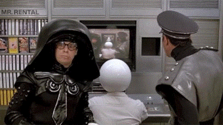 Spaceballs characters including a person in a black hooded leather jacket and one with a white spherical head