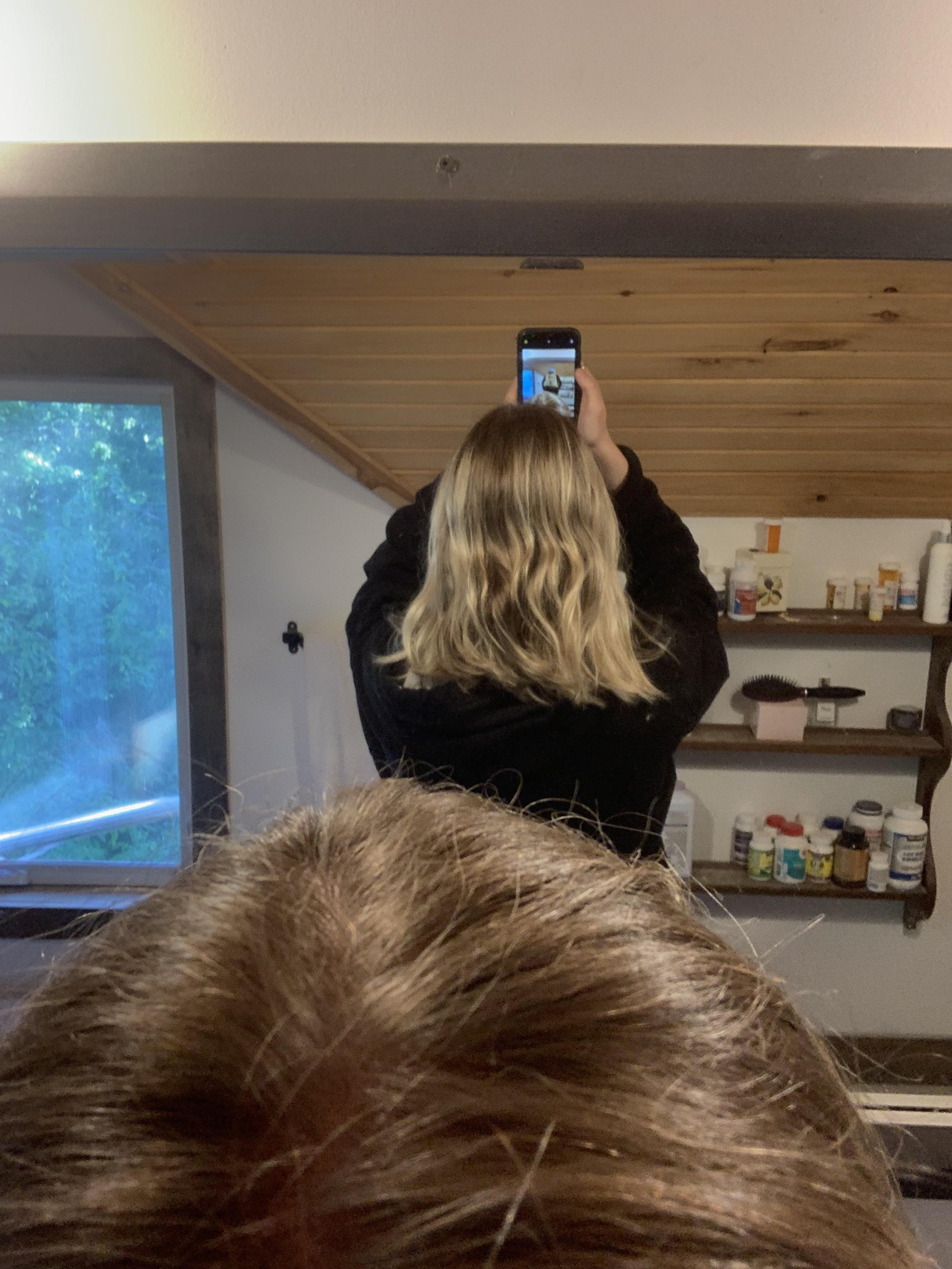 Blonde woman in a black hoodie taking mirror selfies to show her box dye blonde hair