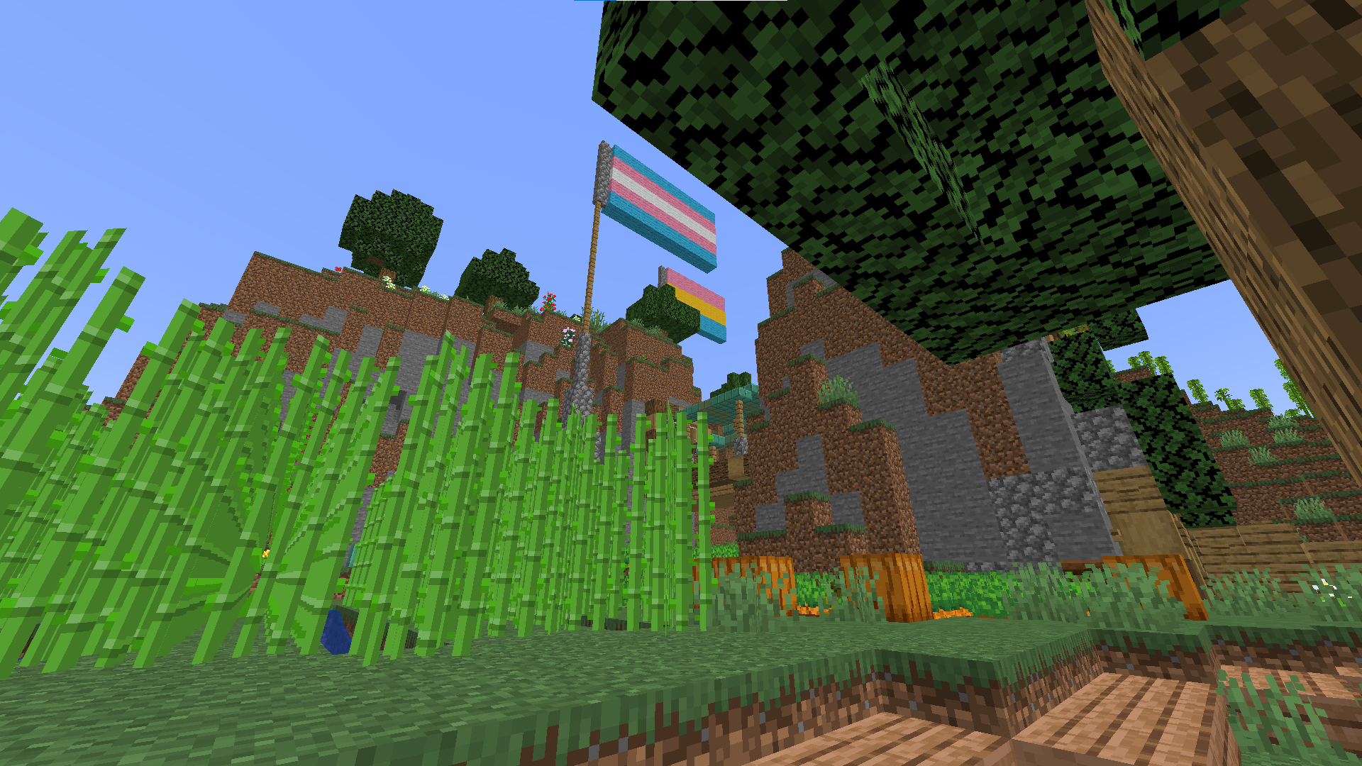 Minecraft survival builds featuring a base with flags, paths, and foliage in a beautiful landscape.