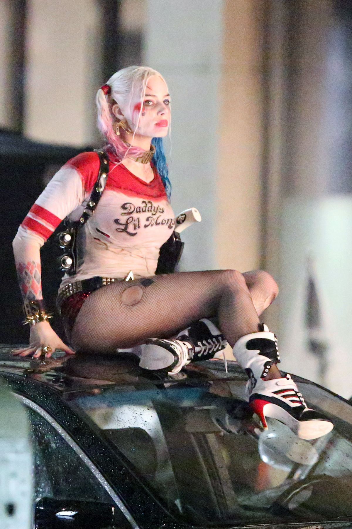 Margot Robbie as Harley Quinn in a red and white cropped top and short shorts with an umbrella