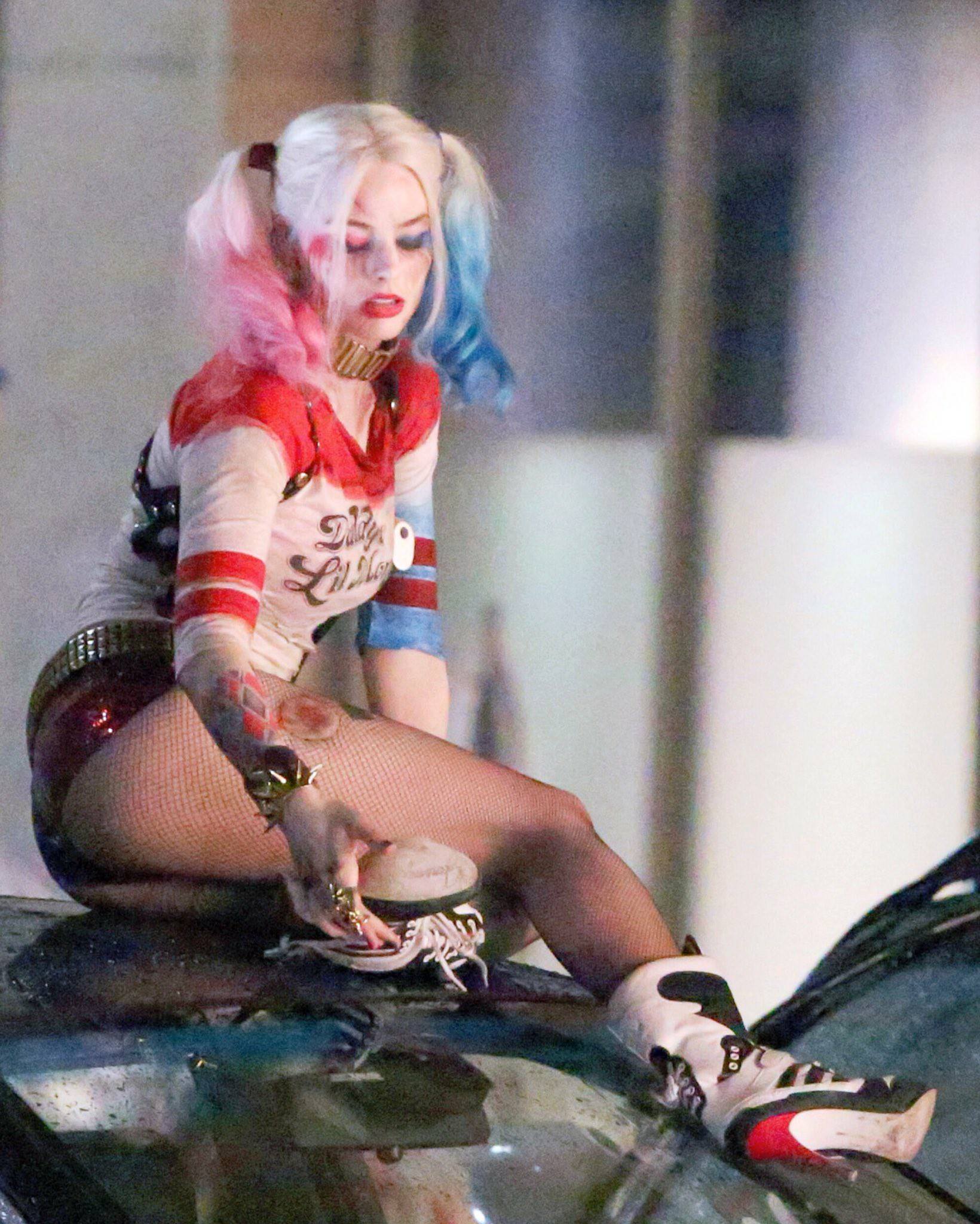 Margot Robbie as Harley Quinn in a red and white cropped top and short shorts with an umbrella