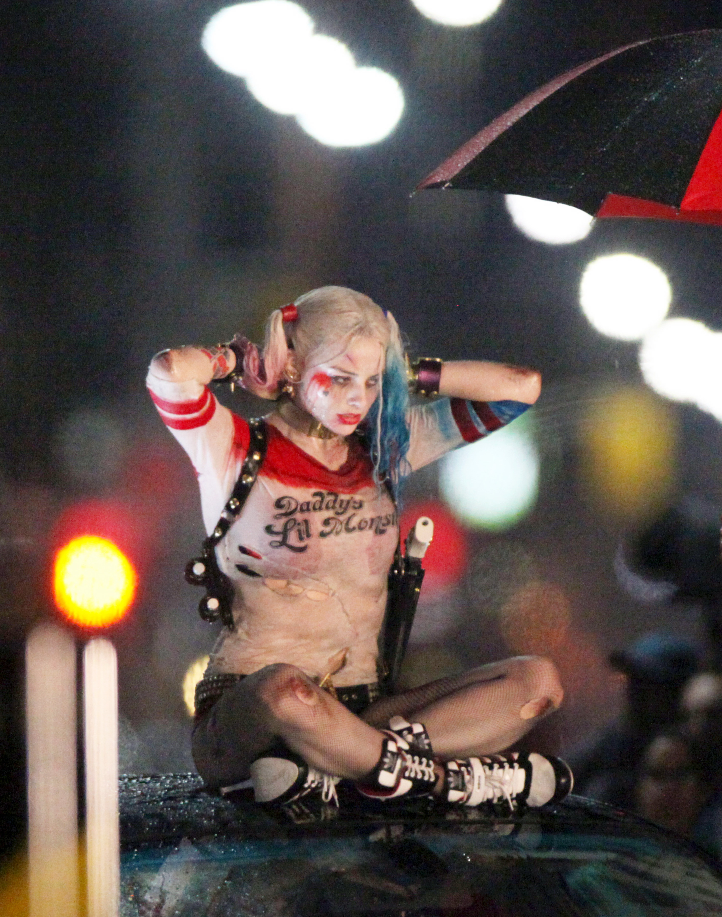 Margot Robbie as Harley Quinn in a red and white cropped top and short shorts with an umbrella