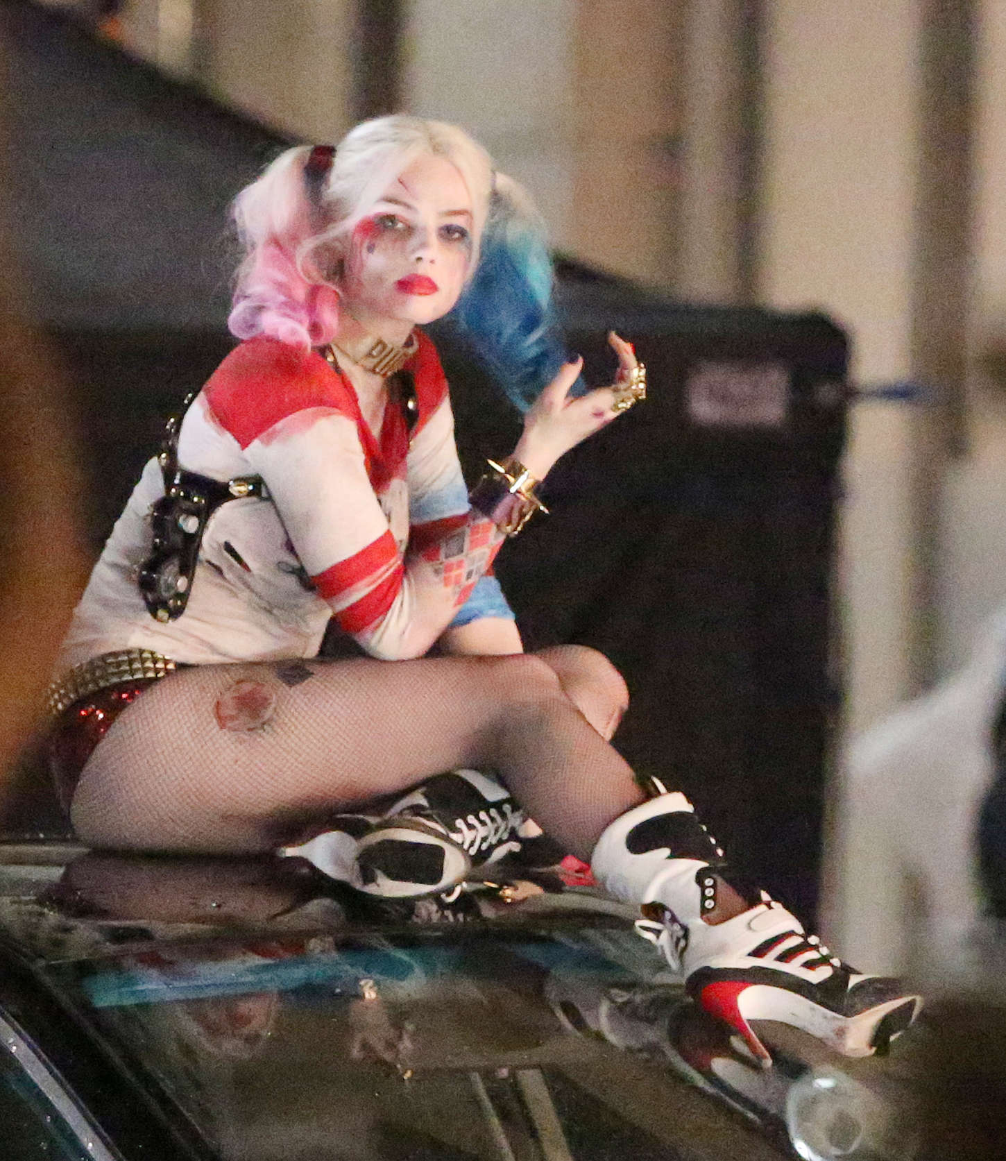 Margot Robbie as Harley Quinn in a red and white cropped top and short shorts with an umbrella