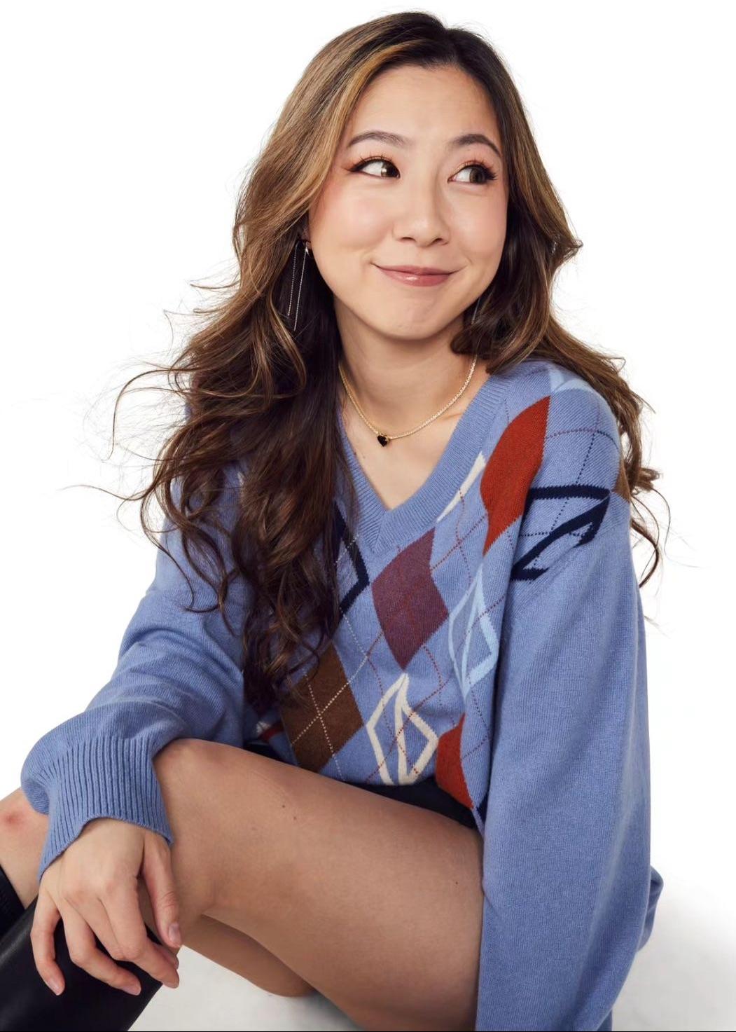 Fuslie posing in a blue argyle wool sweater and black boots