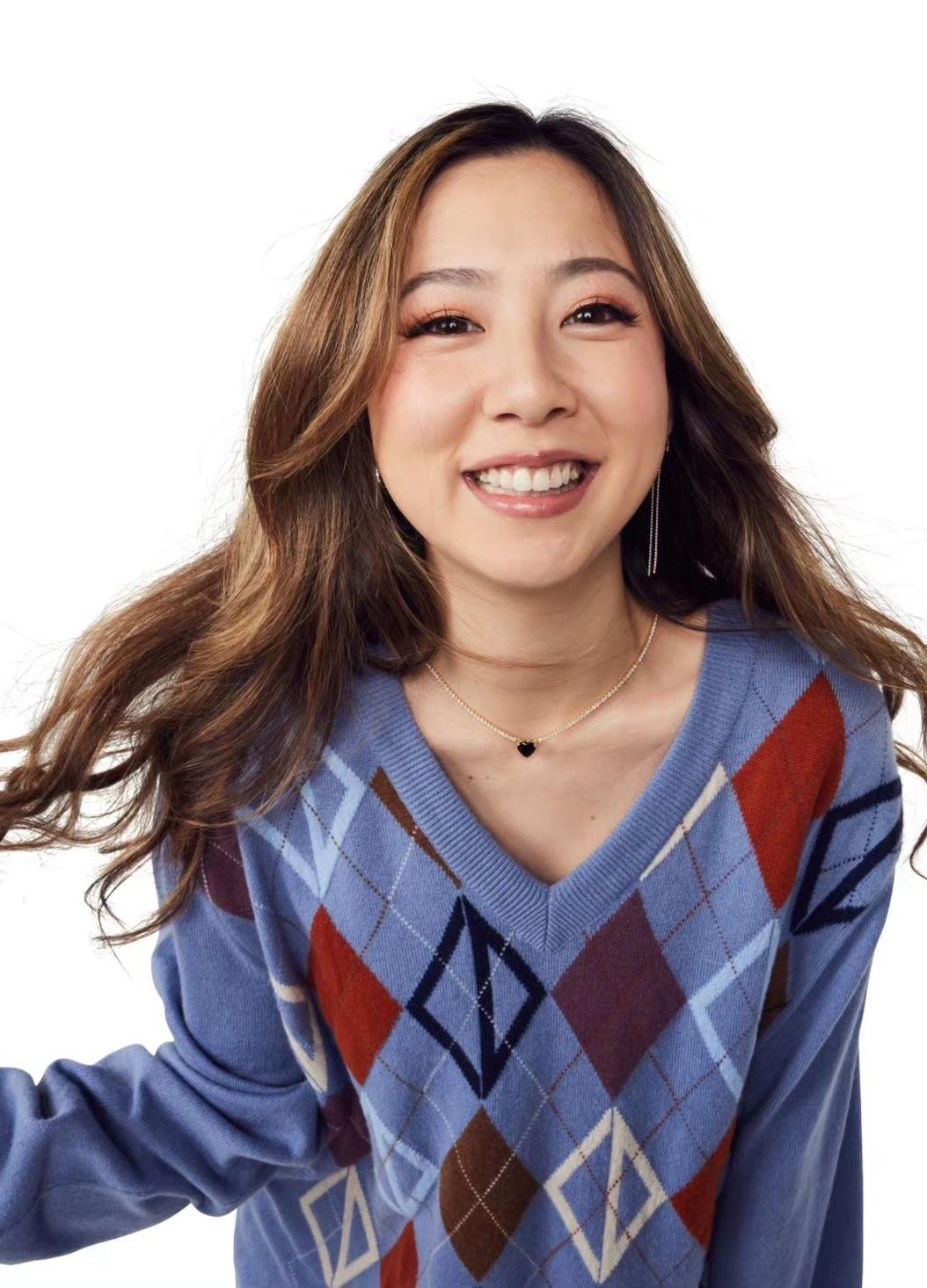 Fuslie posing in a blue argyle wool sweater and black boots