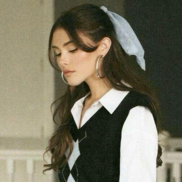 Madison Beer with long brown hair and tanned skin wearing a white dress, black clothing, and a blue wool sweater