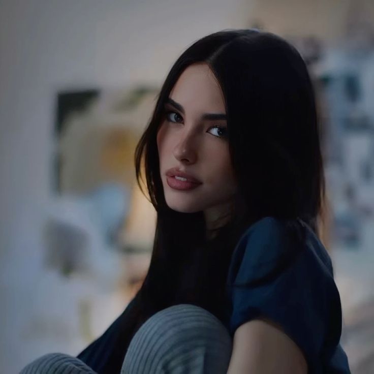 Madison Beer with long brown hair and tanned skin wearing a white dress, black clothing, and a blue wool sweater