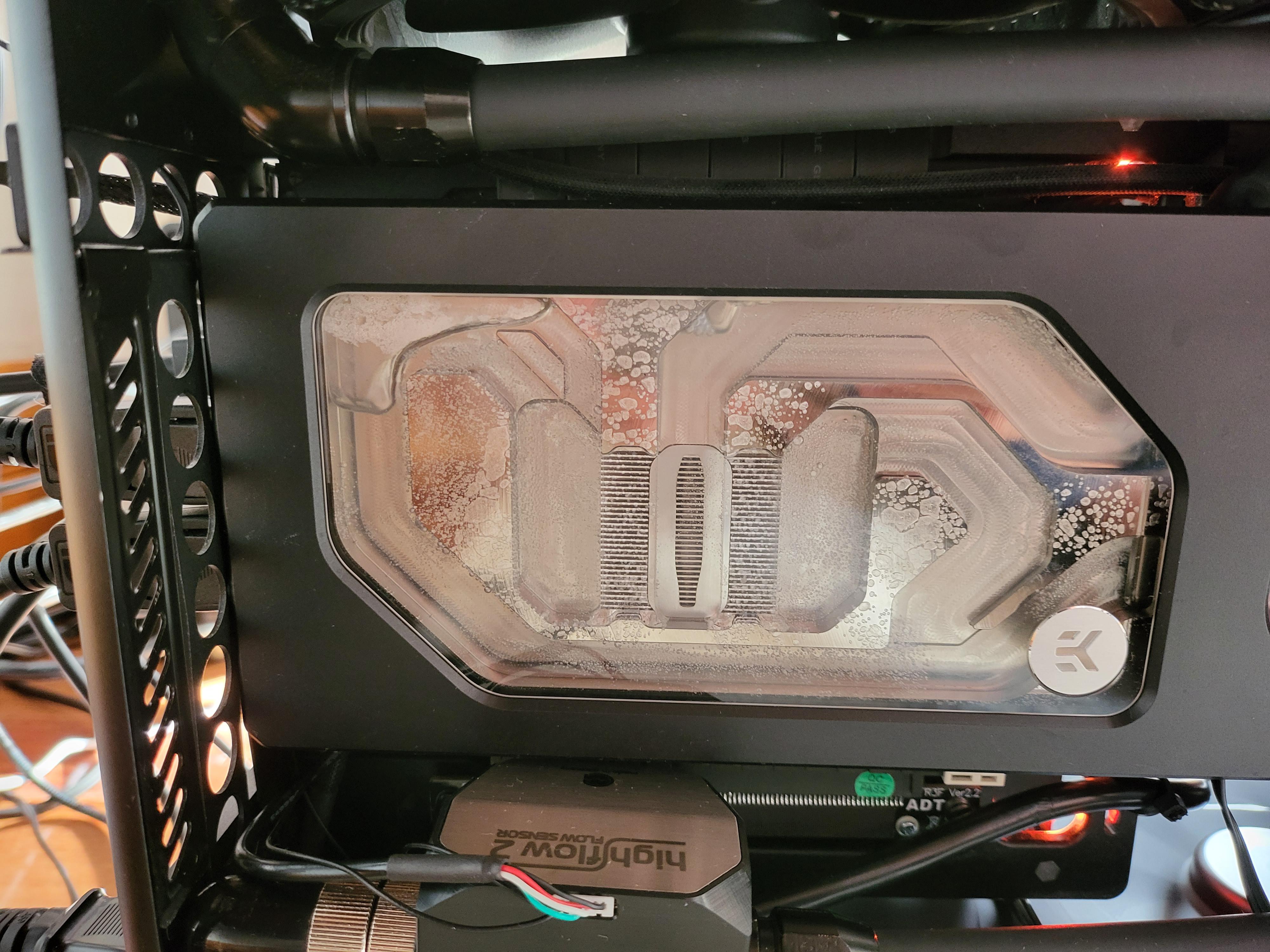 Close-up of a custom gaming pc build liquid cooling reservoir with a flow sensor and bubbles in the waterblock