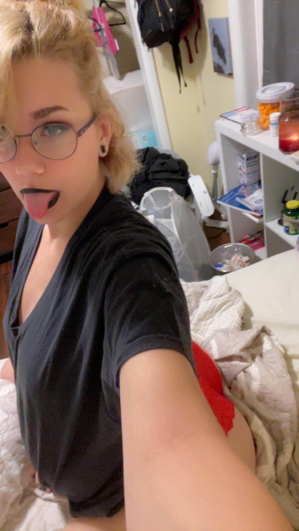 Pregnant blonde woman in a black t-shirt and panties posing with a belly bulge