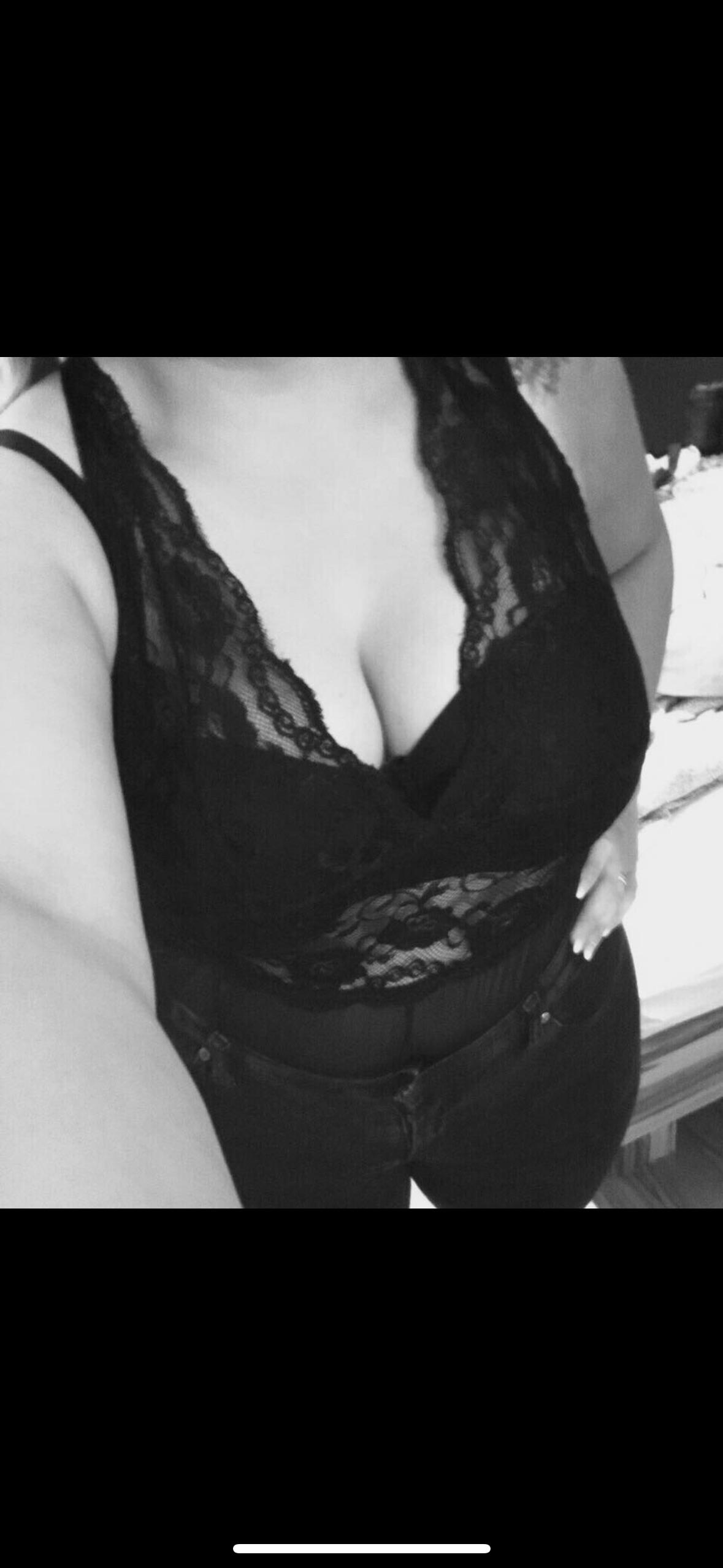 Busty brunette in a white Adidas sports bra and black lace lingerie posing for a selfie