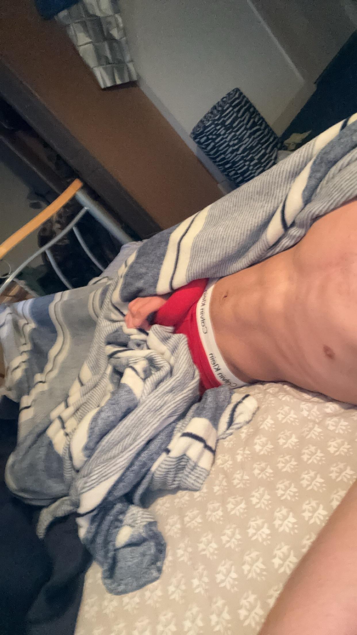 Muscular twunk college student in a bedroom posing shirtless and masturbating with an uncut penis.