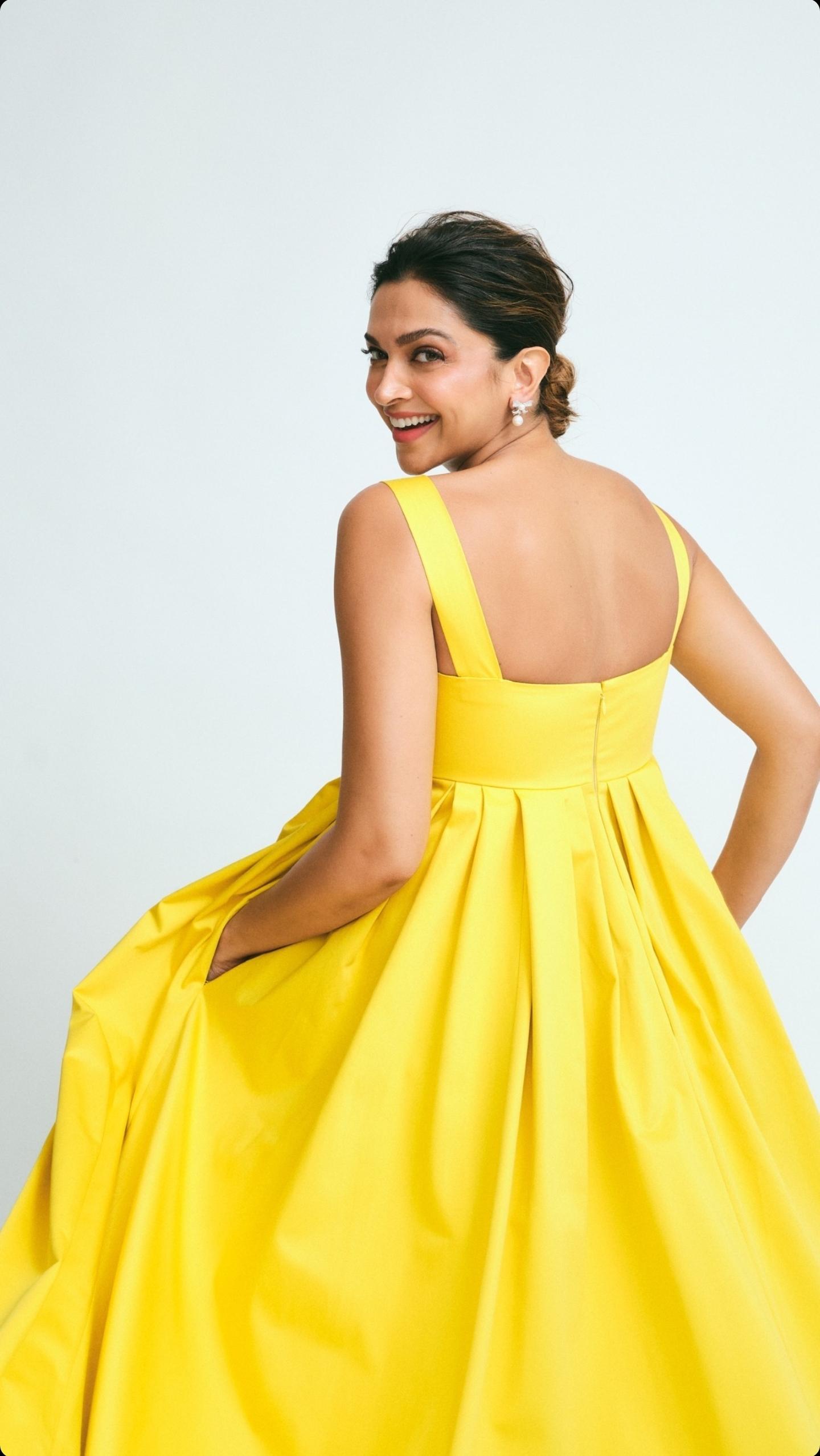 Deepika Padukone, a beautiful Indian actress and desi girl in a yellow dress, resting her chin on her hand.