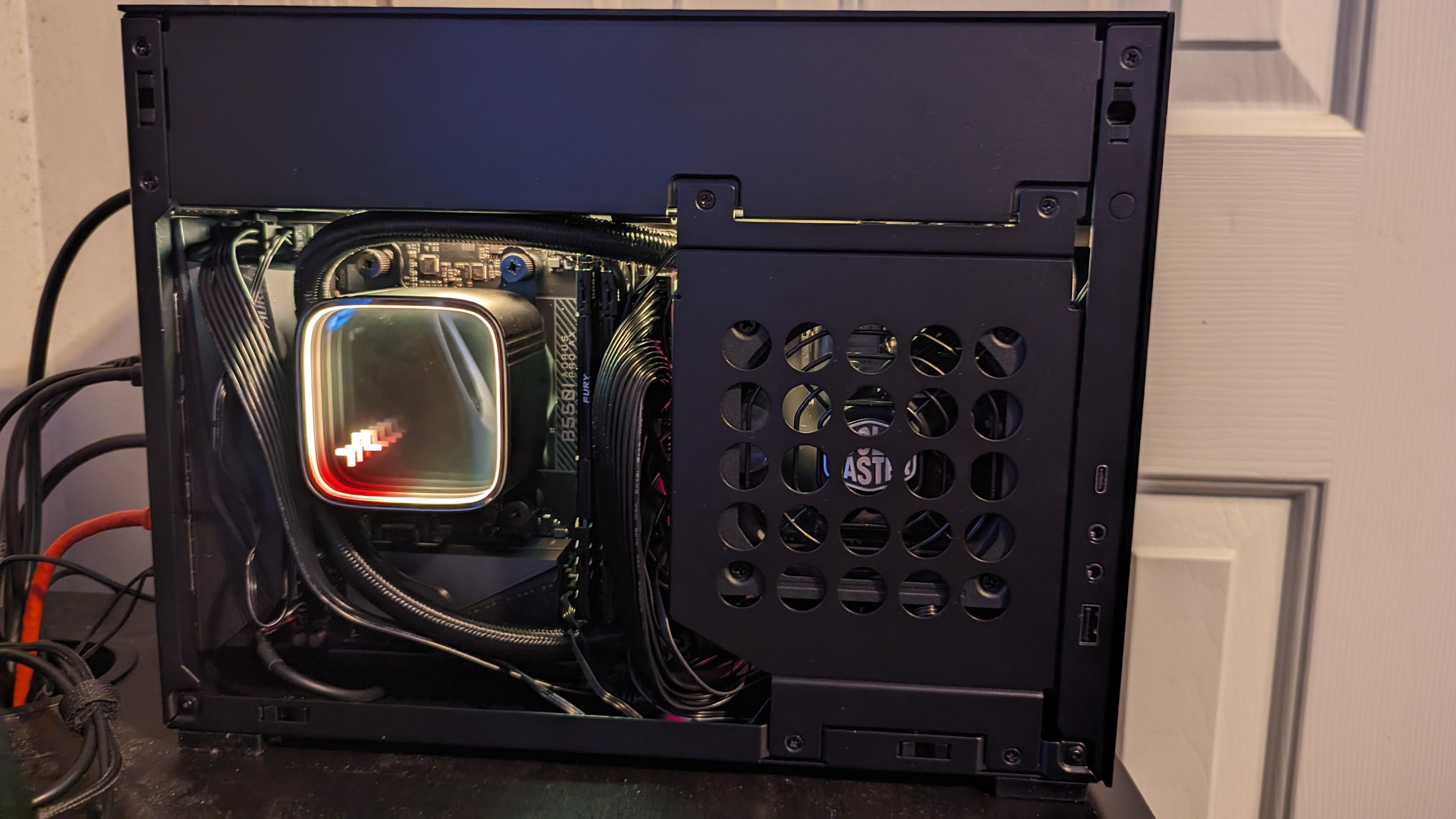 ITX gaming pc setup with a PC tower, RGB keyboard, and monitor on a black desk
