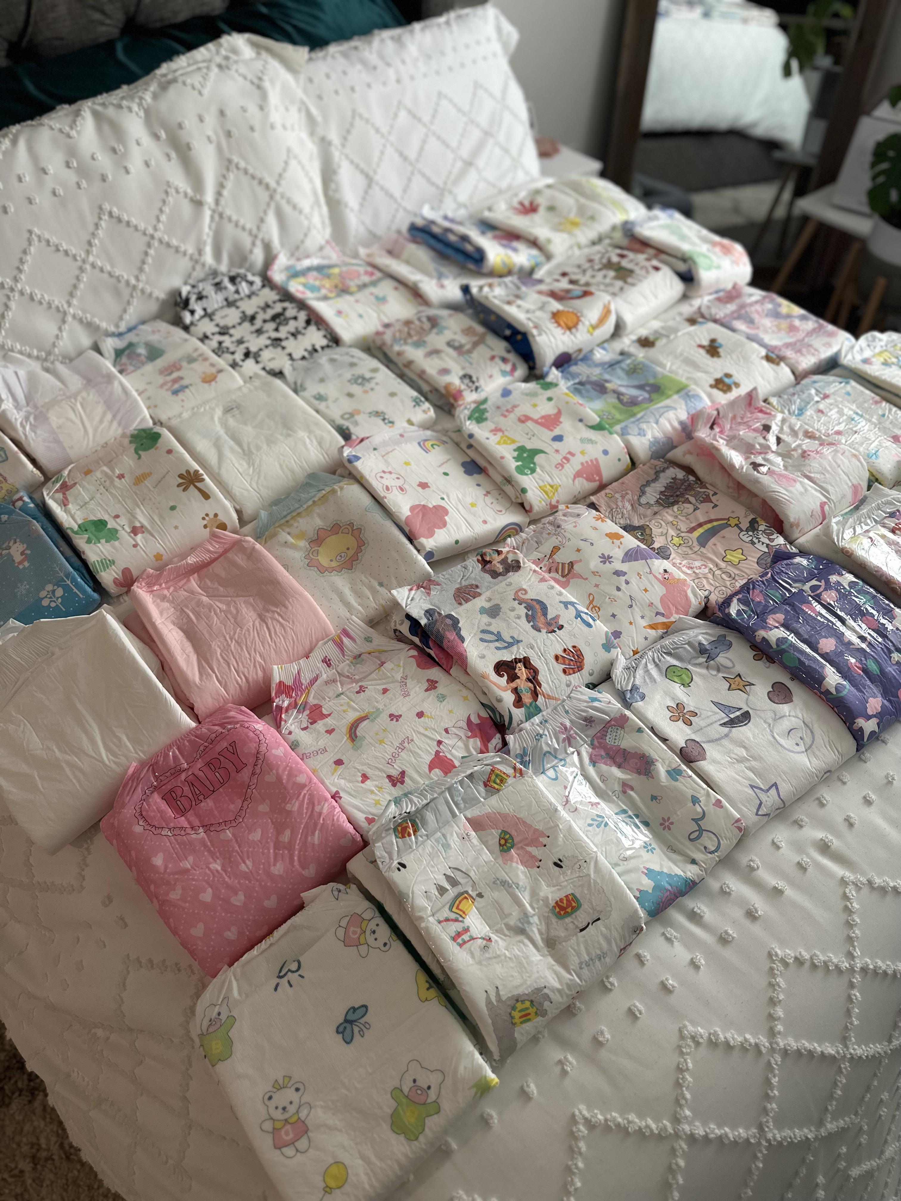 ABDL puffies with floral print, pink, and white patterns on a white bed