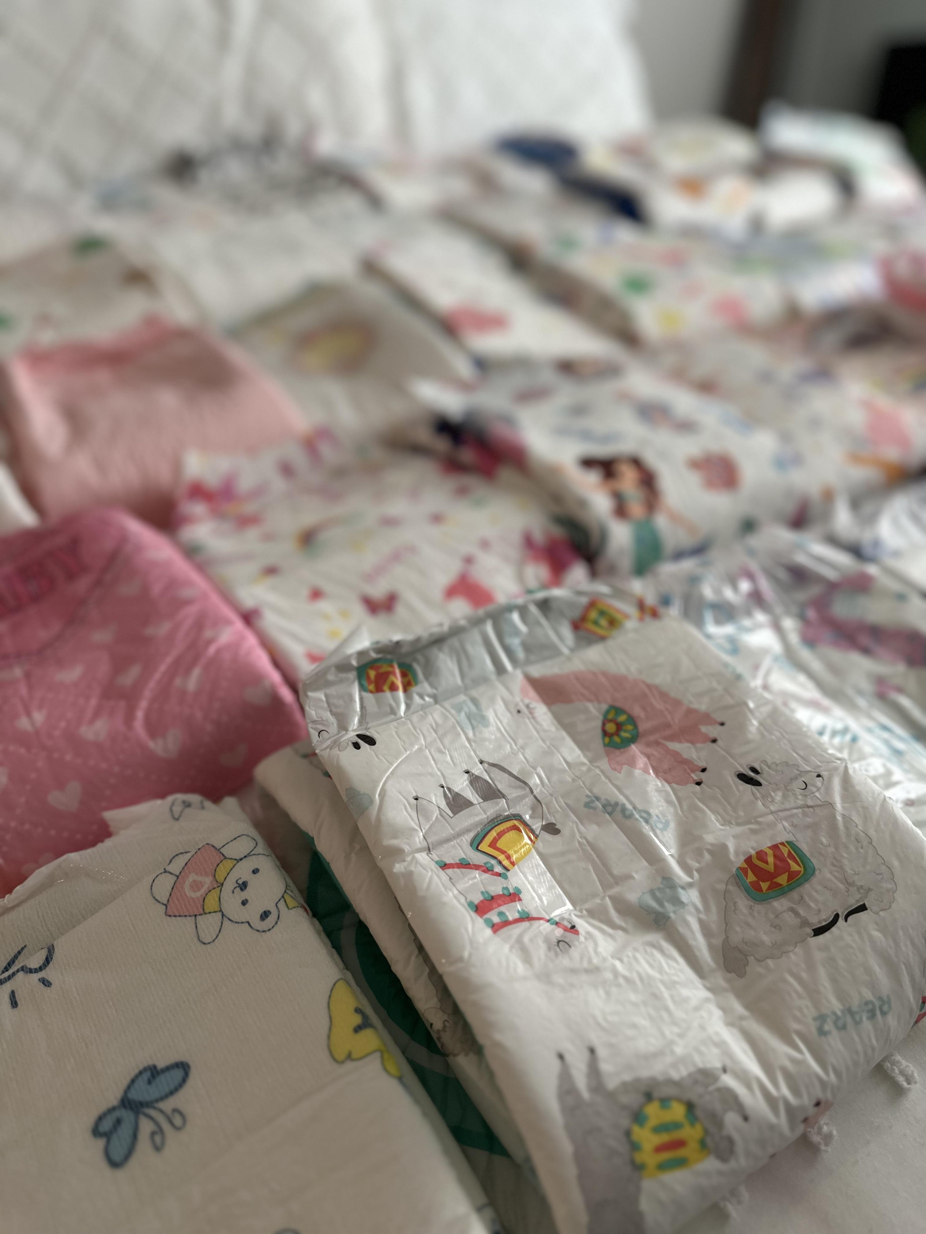 ABDL puffies with floral print, pink, and white patterns on a white bed