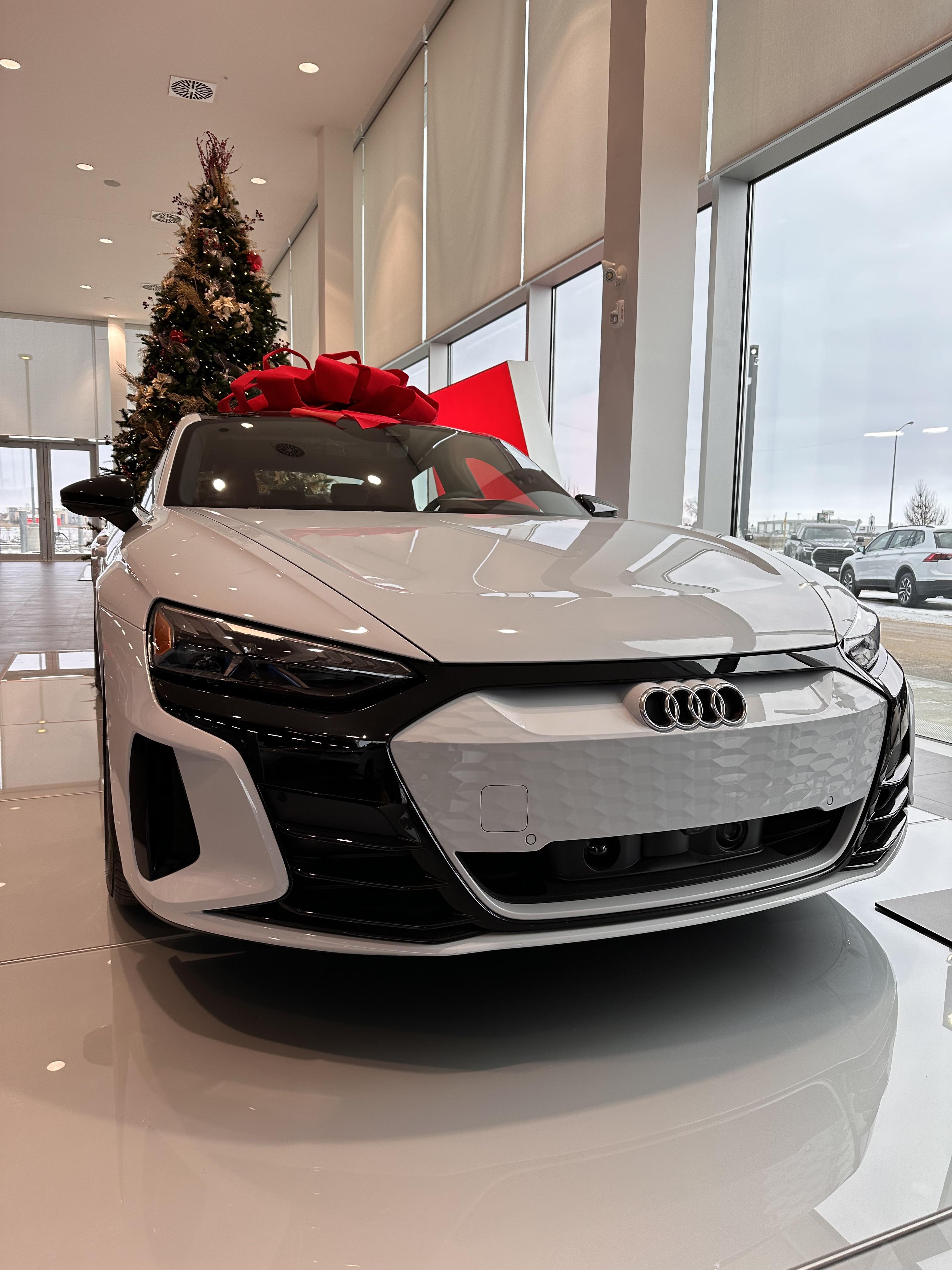 White Audi e-tron GT supercar with a large red bow in an Audi Winnipeg dealership showroom