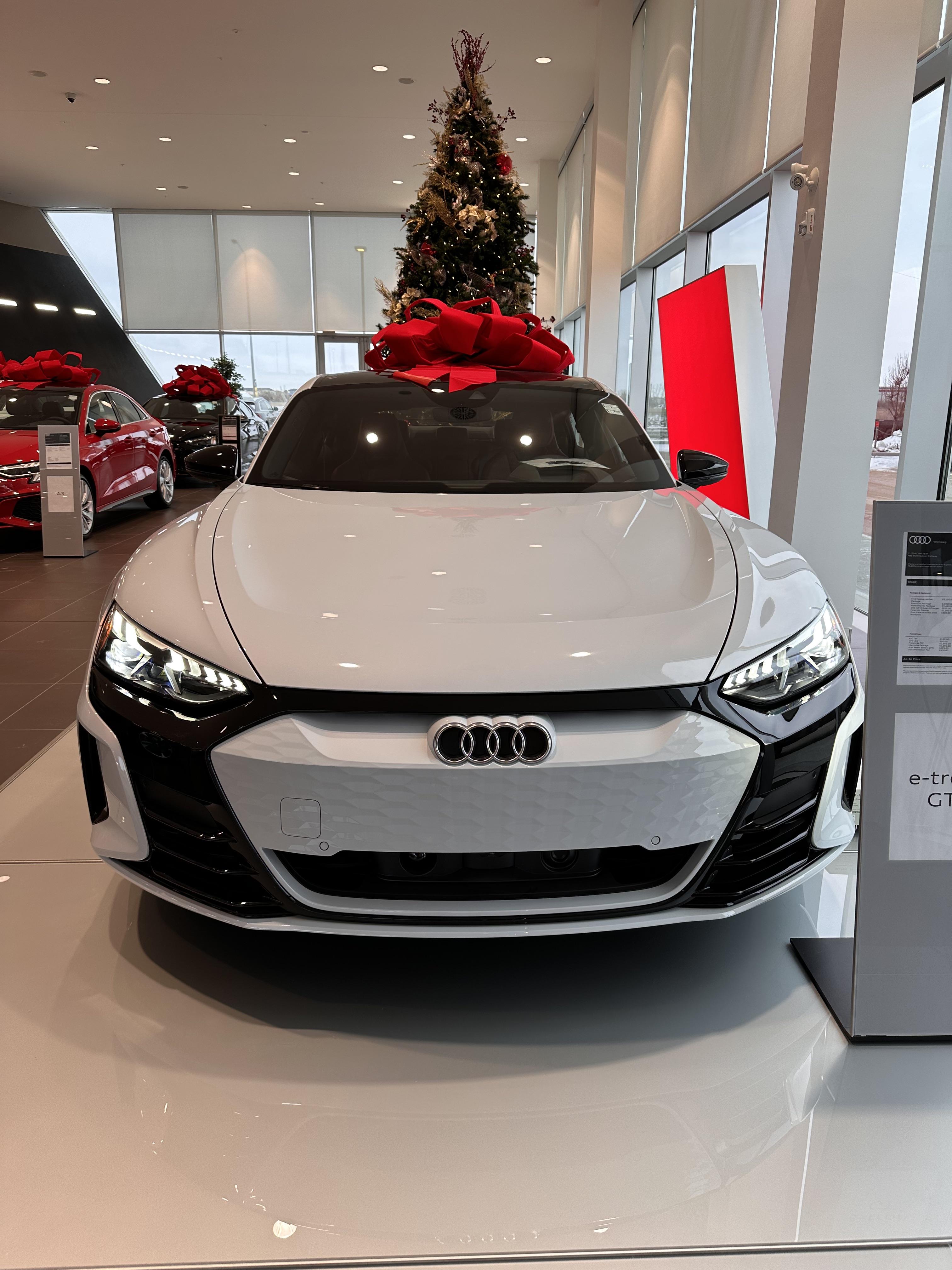 White Audi e-tron GT supercar with a large red bow in an Audi Winnipeg dealership showroom