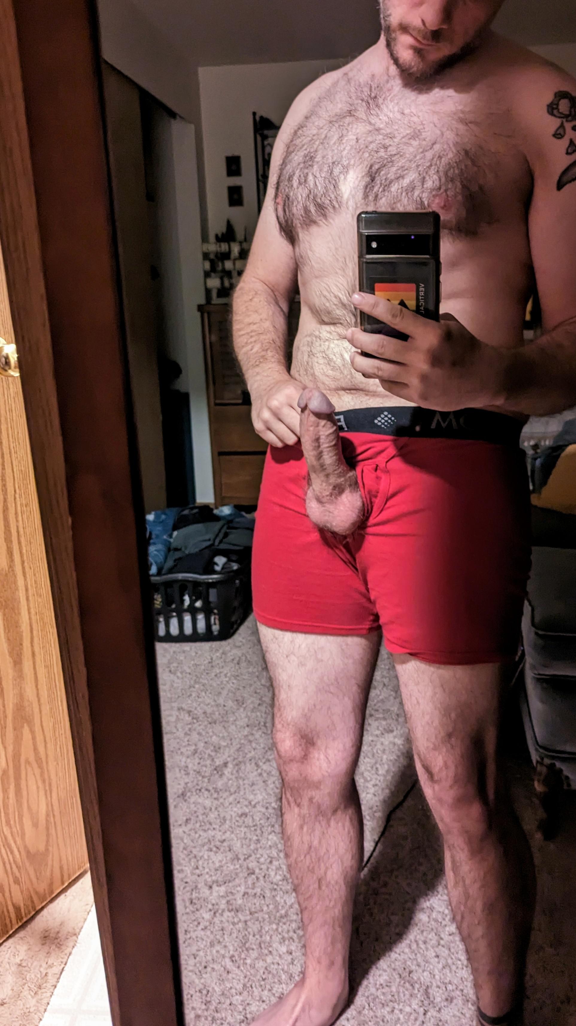 Athletic white man with a tattoo in red underwear taking a pelfie showing his erection in a bedroom mirror