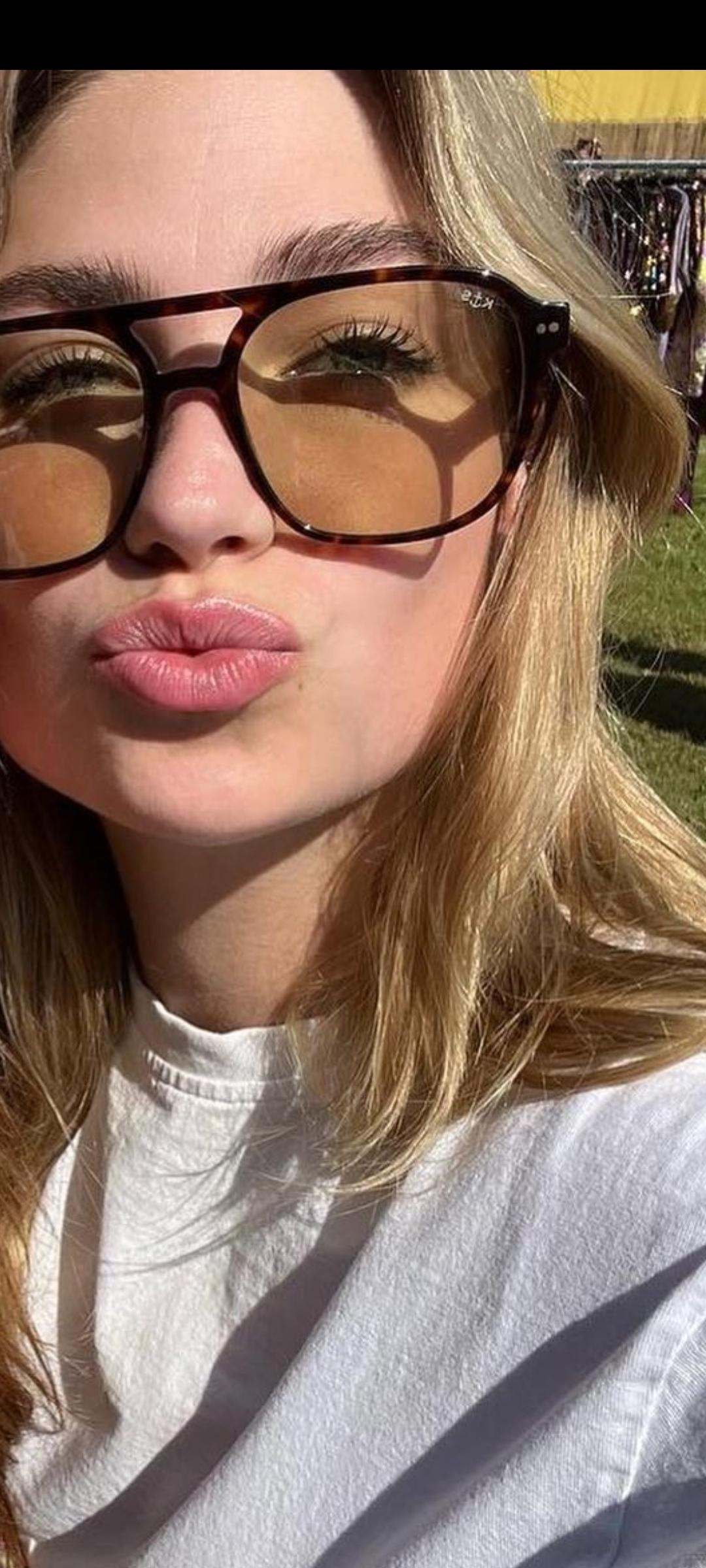Roxy Dekker pouting in a mirror selfie, wearing a white t-shirt, sunglasses, and puffer jackets.
