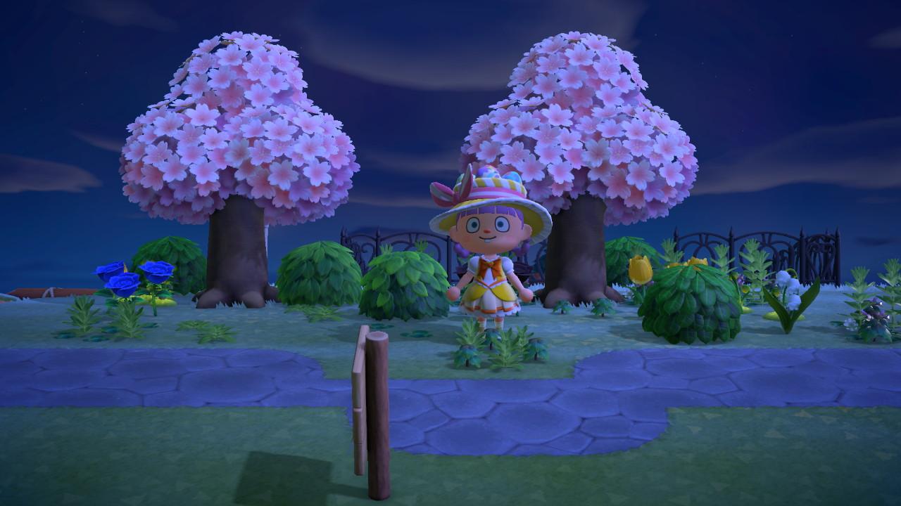 Animal Crossing: New Horizons character in a yellow floral dress and wide-brimmed hat by a bridge with cherry blossom trees