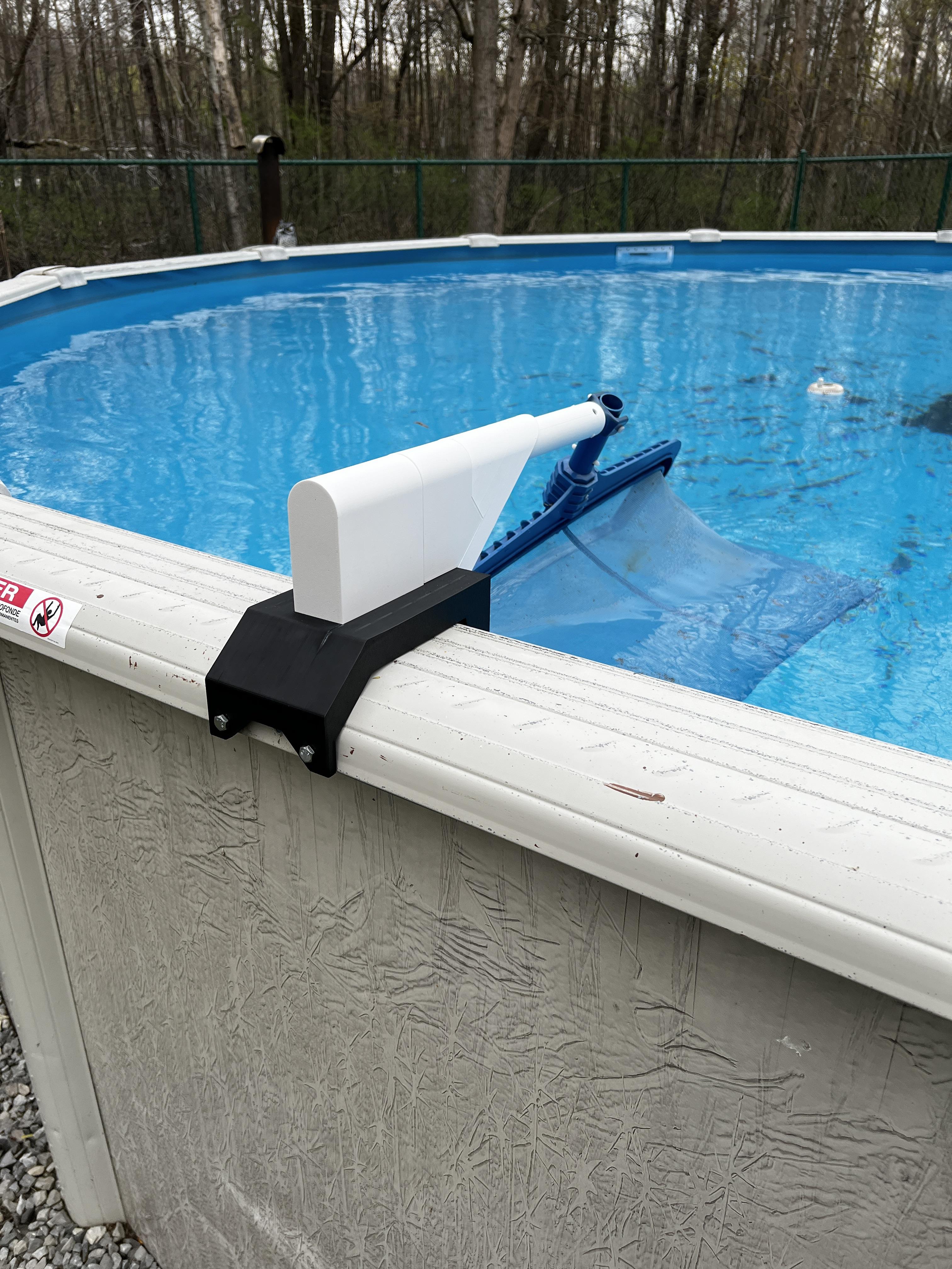 A 3D printed pool leaf skimmer holder attached to the railing of an above-ground swimming pool.