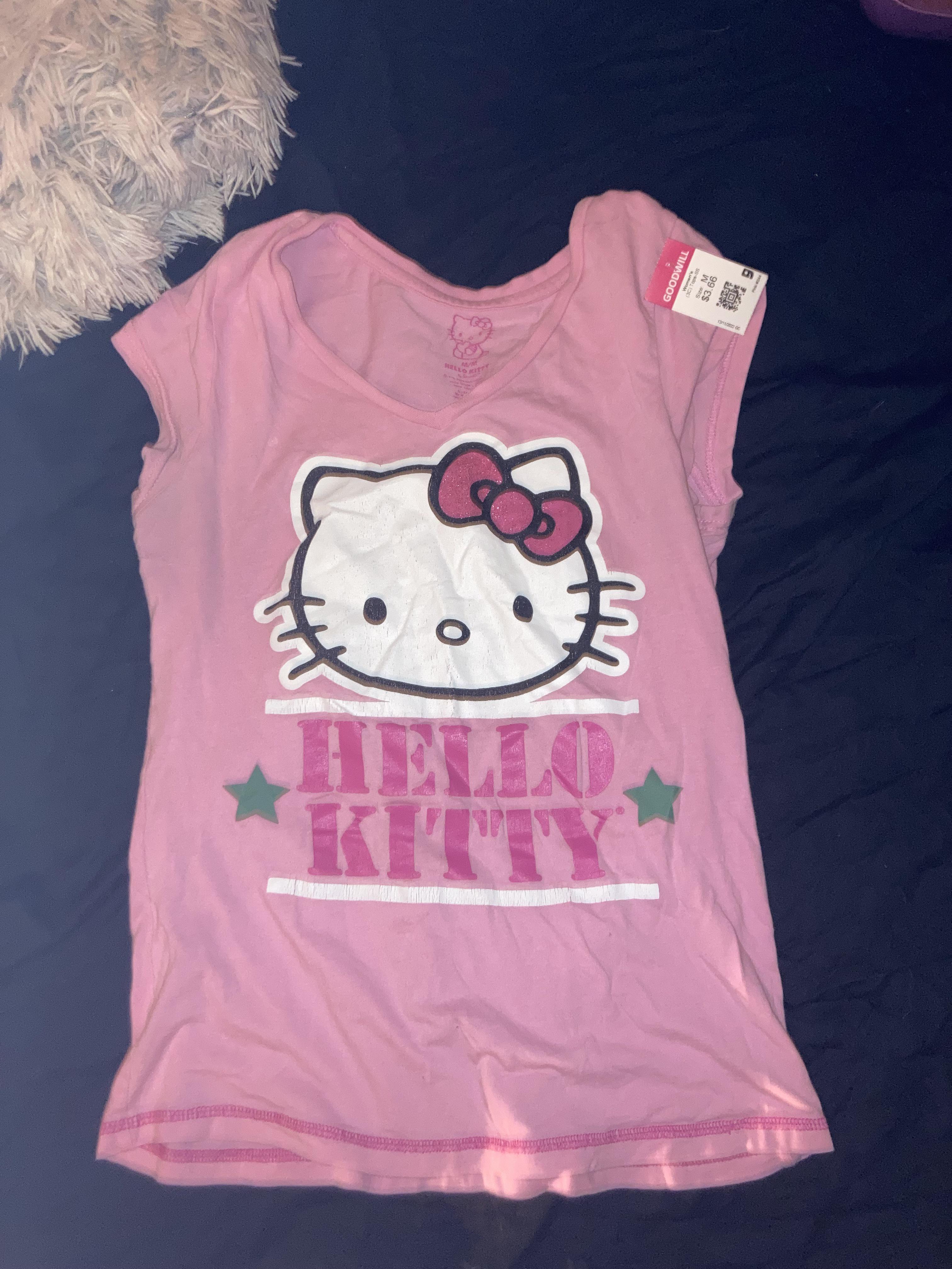 Thrift haul featuring a Hello Kitty tank top, sunflower white shirt, pink tutu top, and a striped turtleneck