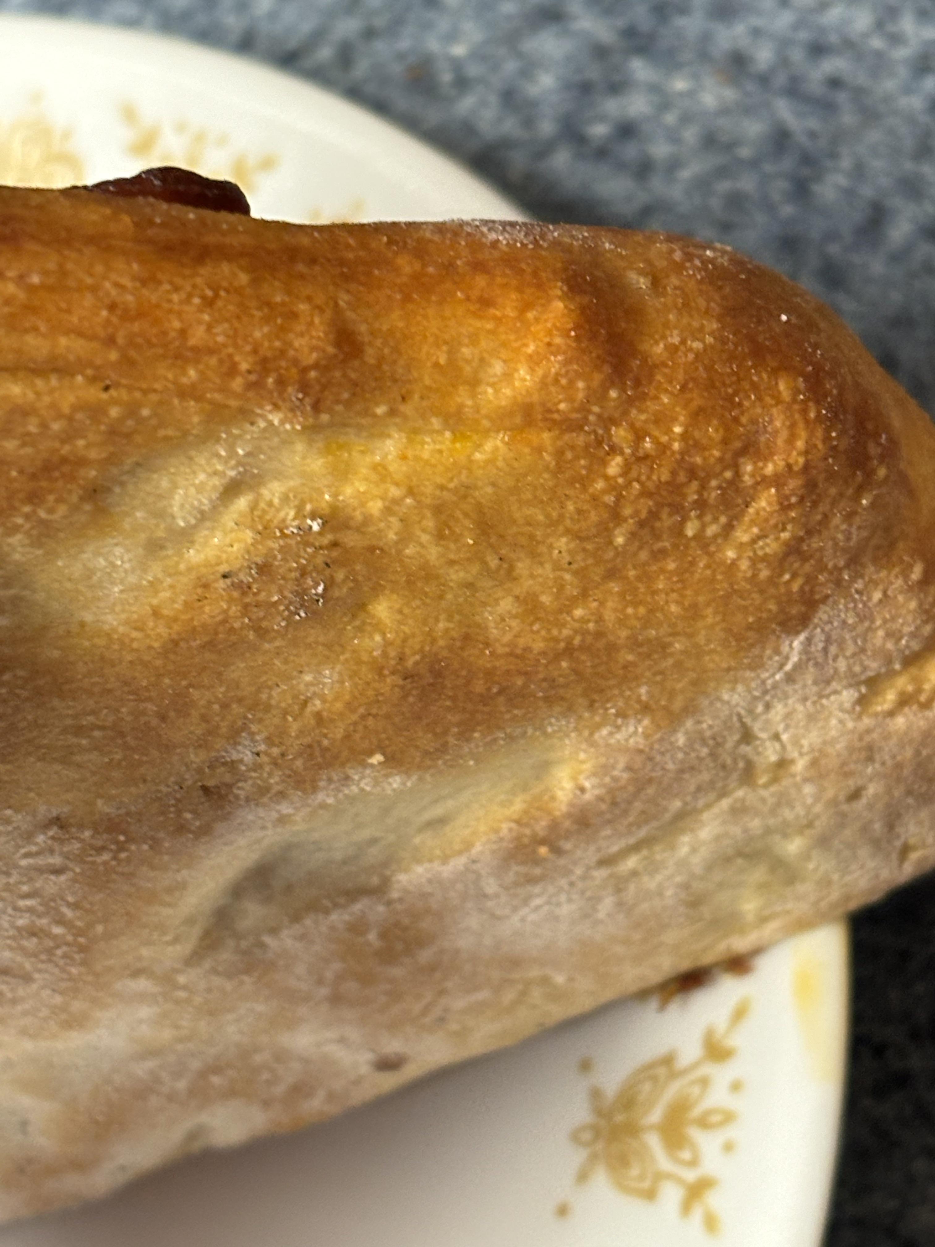 Turkey pepperoni pizza and a thick loaf of bread in an indoor kitchen