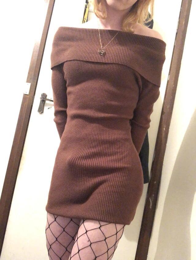 Blonde slim trans girl in a brown off-the-shoulder dress and black crop top posing for selfies
