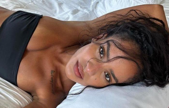 Narah Baptista in a black dress, white lace top, and grey suit, featuring her tattoos and tanned skin