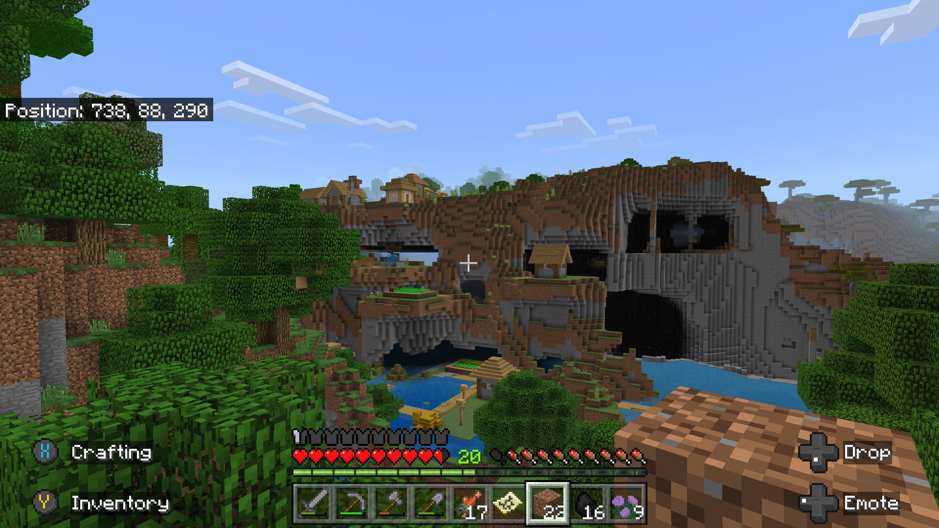Minecraft survival build of a village built into a rocky cliffside overlooking water