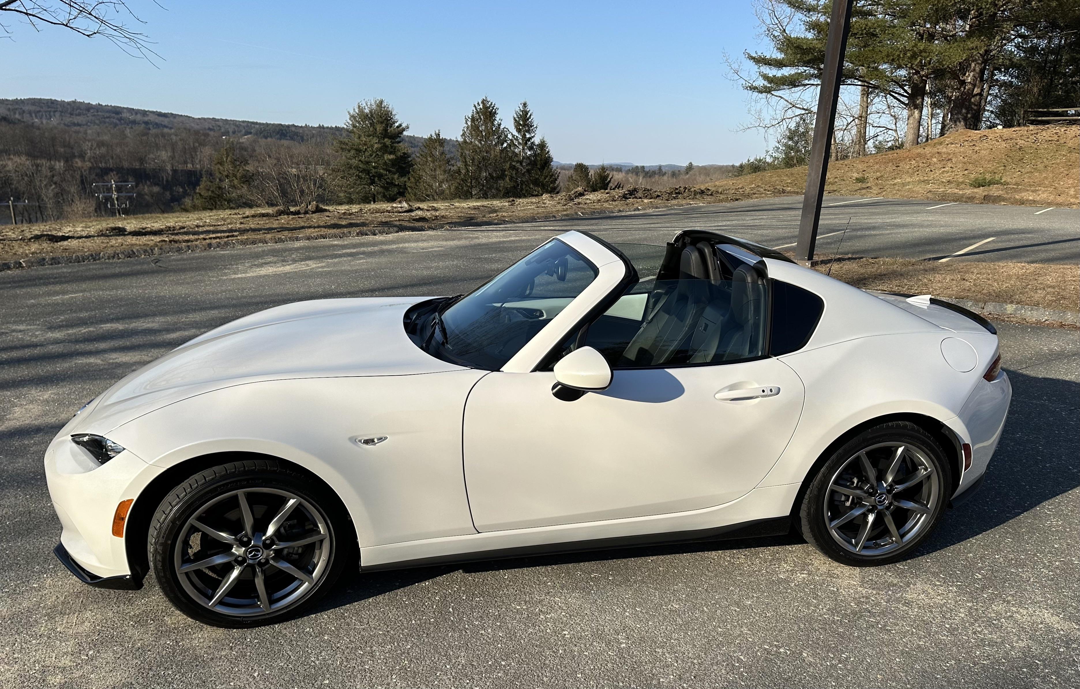 White Mazda MX-5 Miata RF convertible in an outdoor parking lot with a close-up of the car interior dashboard