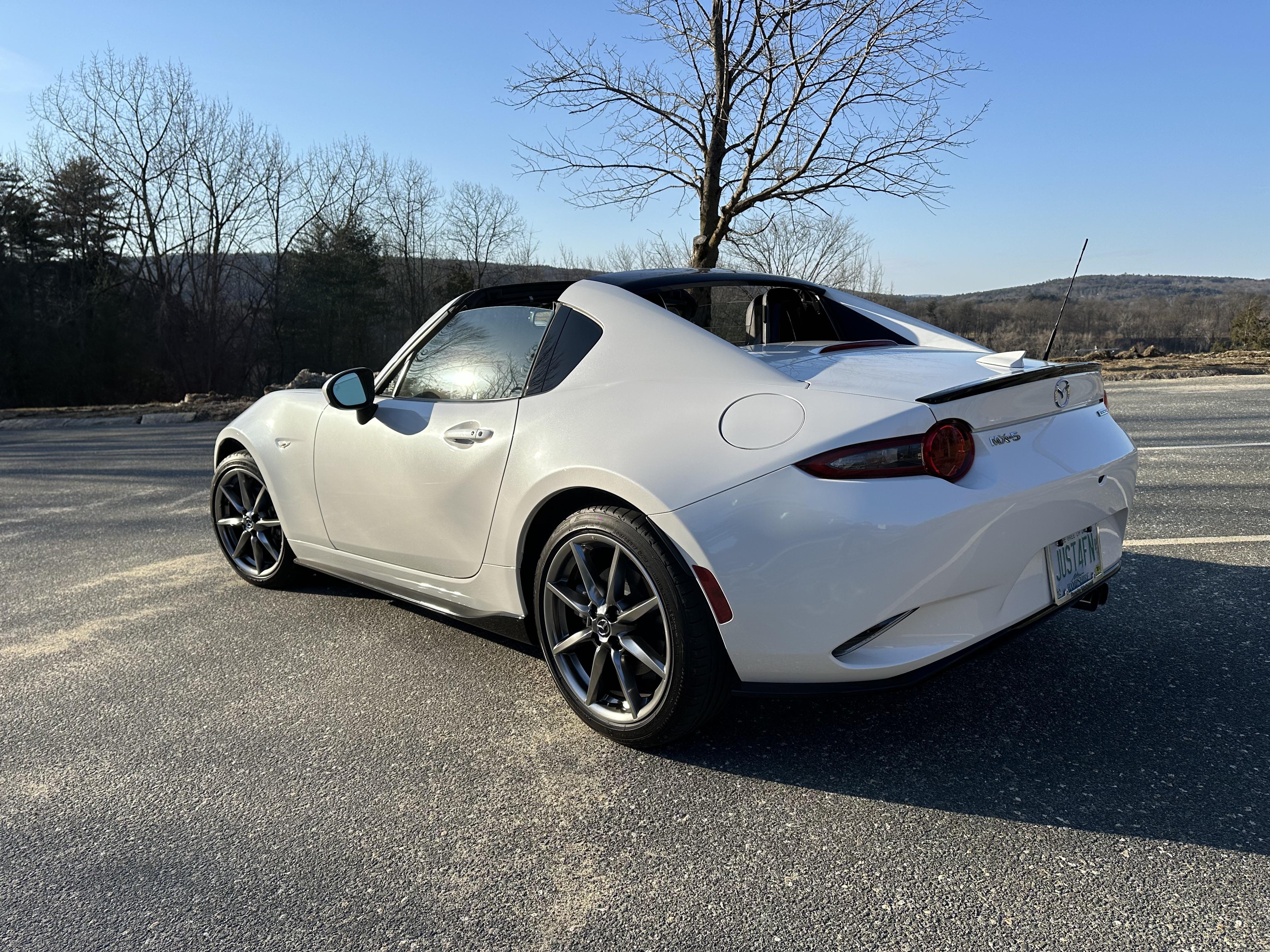 White Mazda MX-5 Miata RF convertible in an outdoor parking lot with a close-up of the car interior dashboard