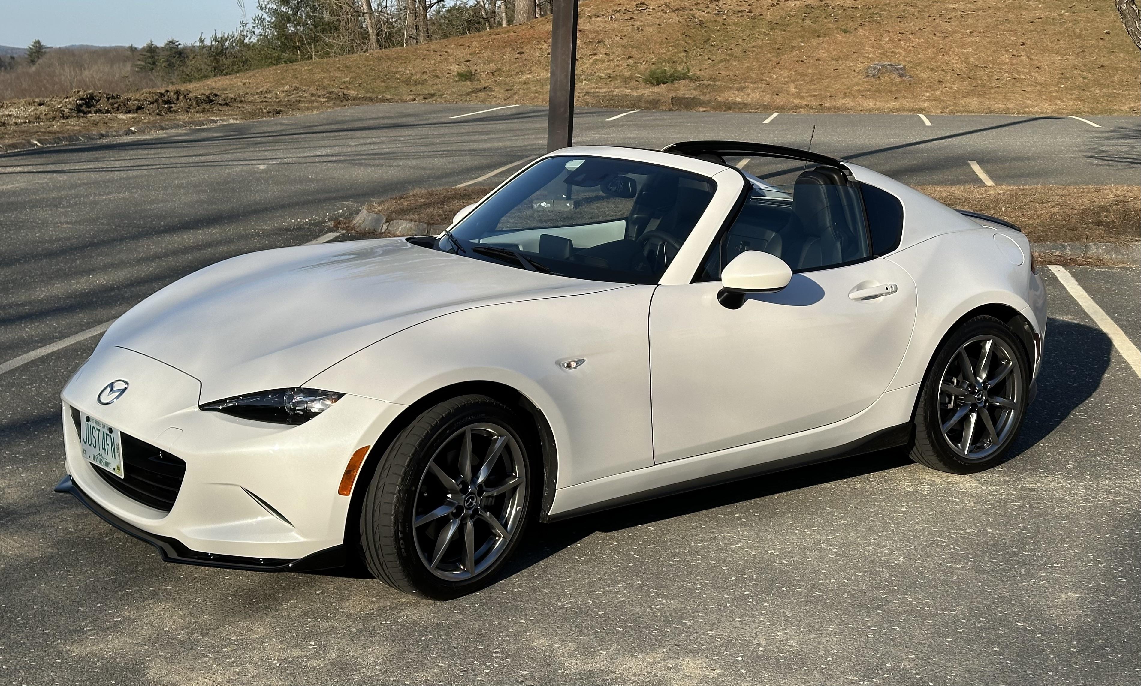 White Mazda MX-5 Miata RF convertible in an outdoor parking lot with a close-up of the car interior dashboard