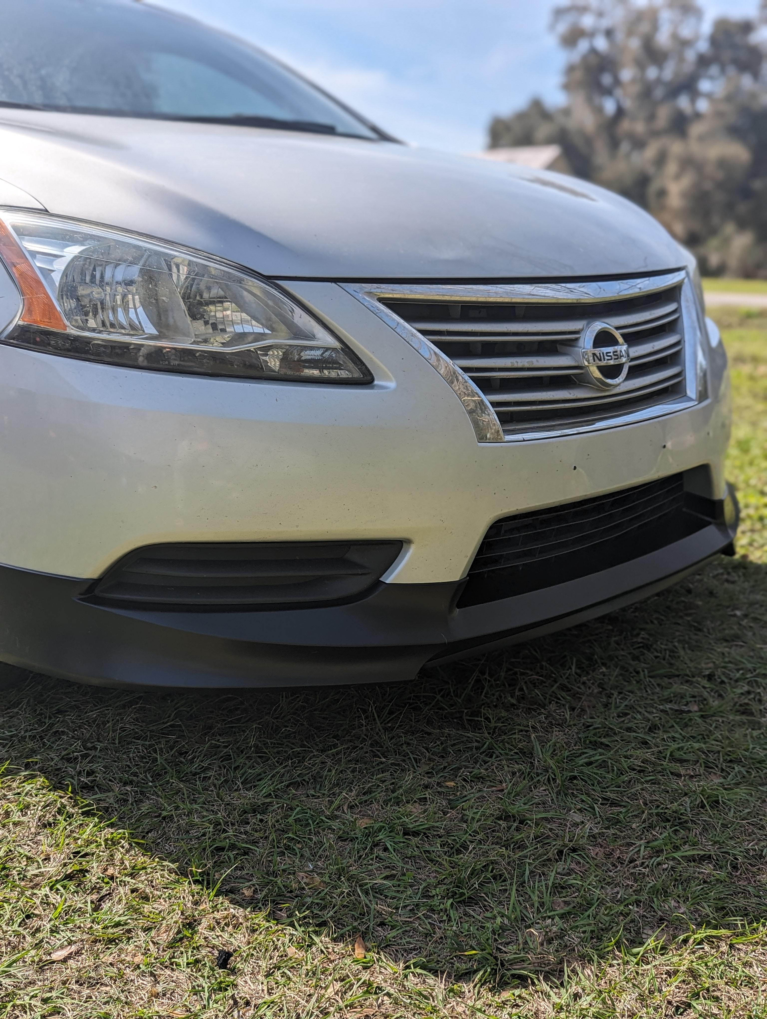 Close-up of a silver Nissan car parked on grass