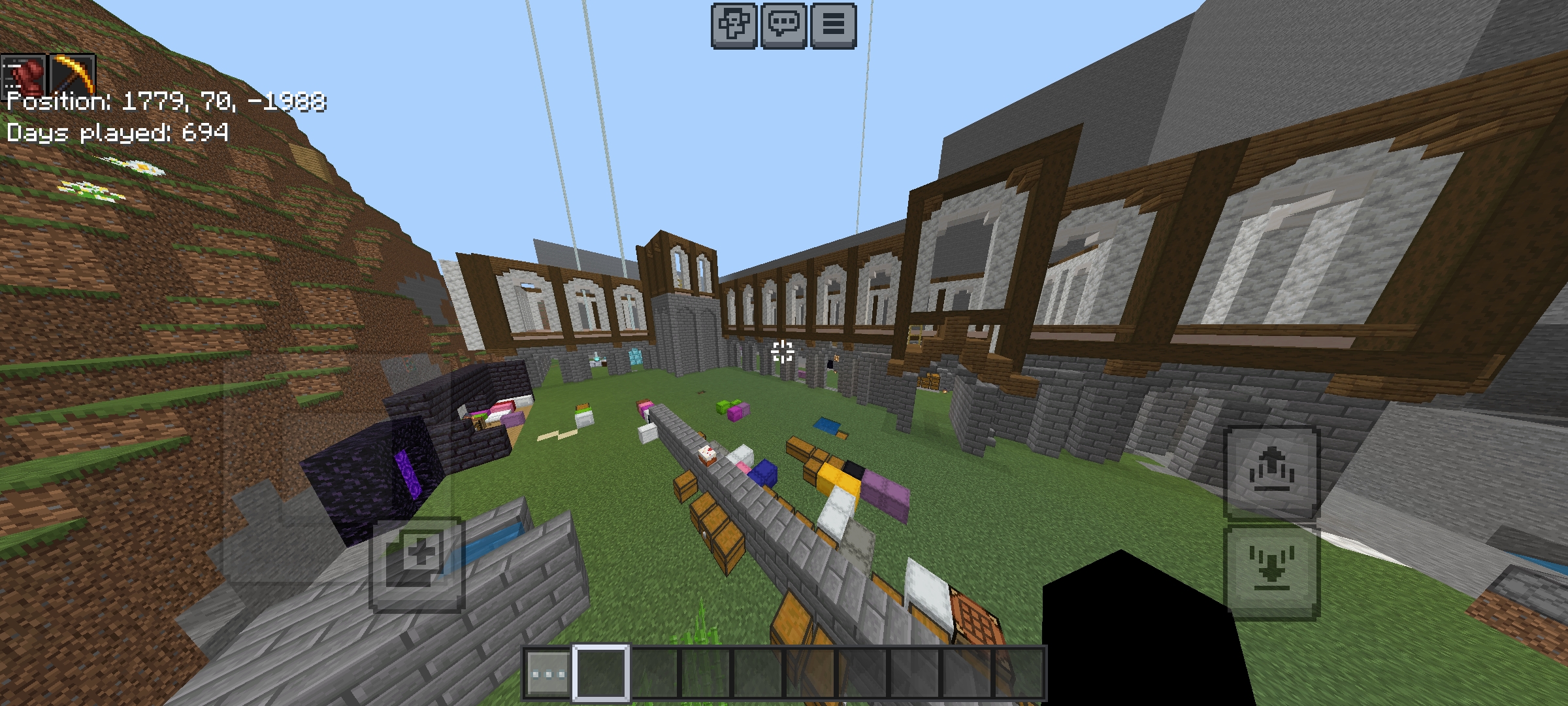 Minecraft mega build of a large wooden mansion situated among green hills and mountains.