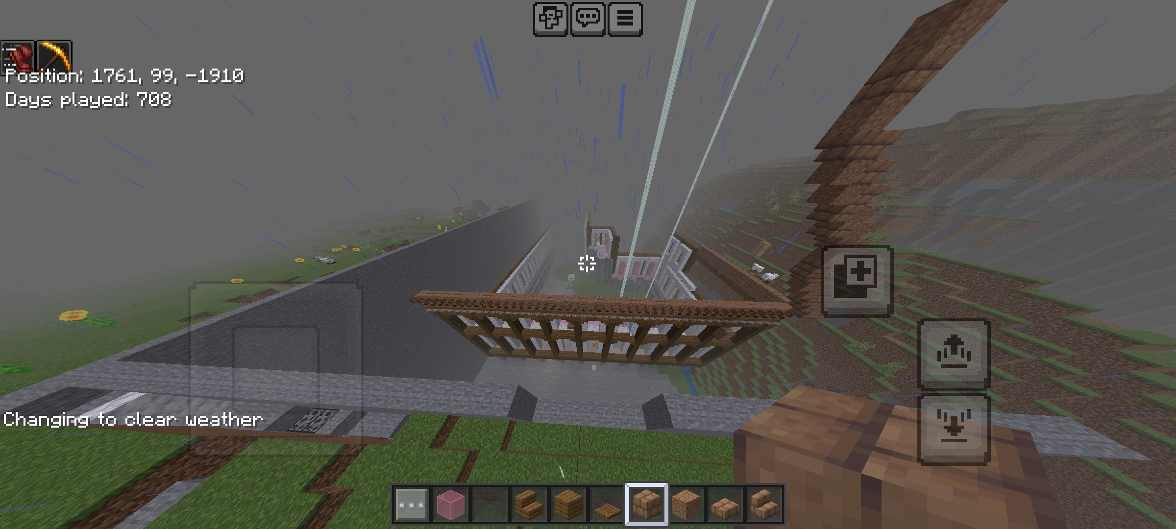 Minecraft mega build of a large wooden mansion situated among green hills and mountains.