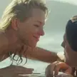 Naomi Watts and a man sharing passionate kisses and embracing outdoors by the water and indoors on a bed