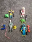 Ghostbusters toys from the 80s, including Slimer, scattered on a grey carpet.
