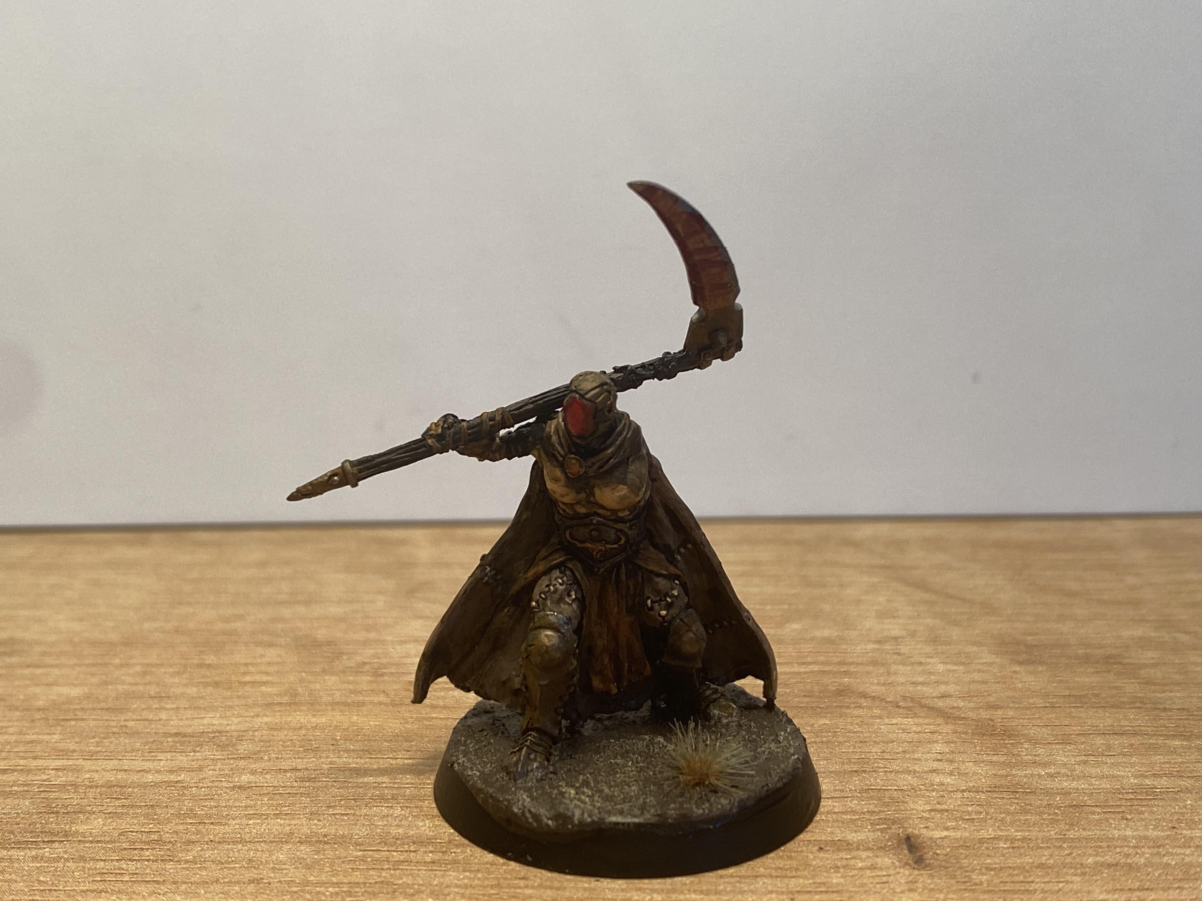 Painted Warhammer miniature of a warrior with a grey beard, tall blue and gold helmet, and an axe on a red base