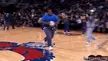 Man in blue athletic wear performing a video game jump stunt off a mini-trampoline onto a crash mat in an NBA arena