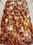 Homemade Amish apple fritter bread with white glaze on a wire cooling rack